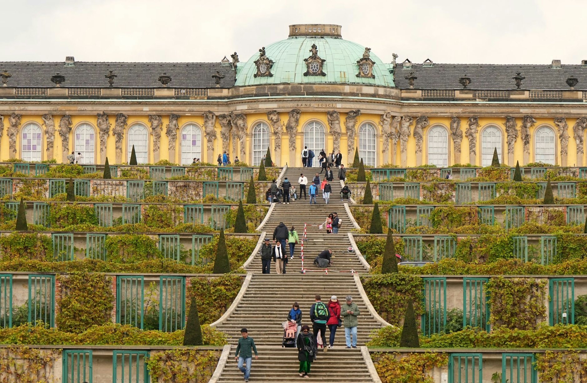 ARCHIV - Touristen gehen bei sonnigem Wetter auf der Treppe zum Schloss Sanssouci.