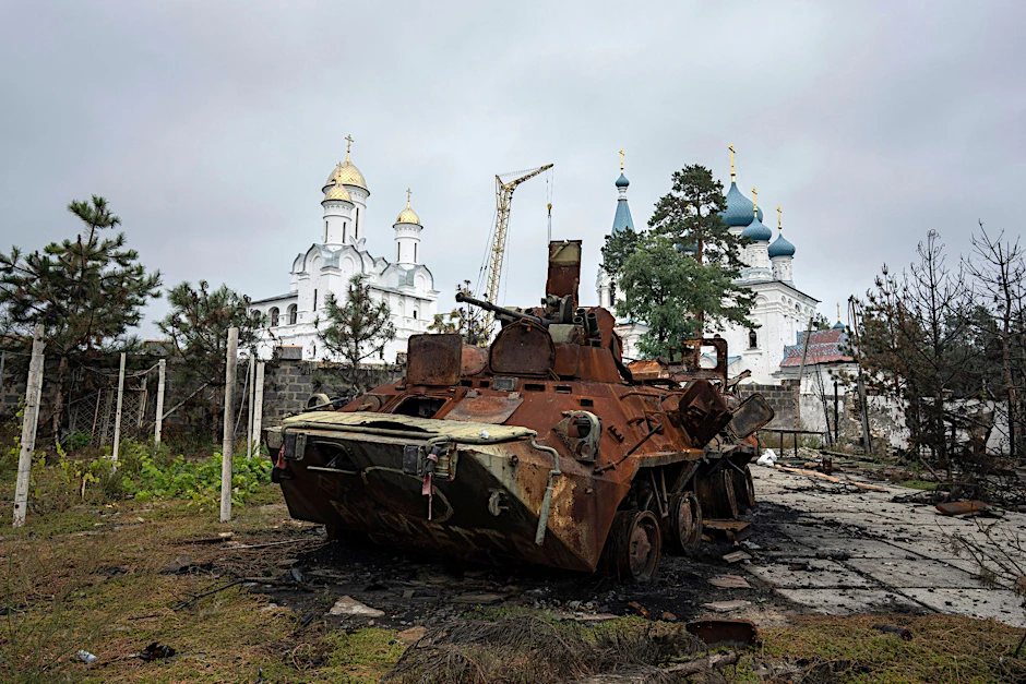 Ein zerstörter russischer Schützenpanzer steht vor einer Kirche in Isjum.