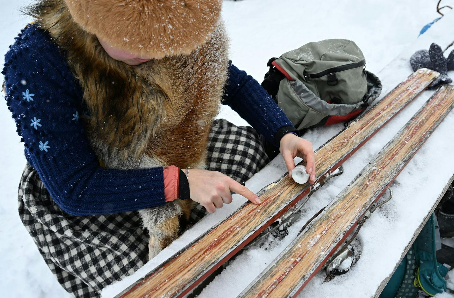 Eine Teilnehmerin wachst ihre Holzskier mit einer Kerze.