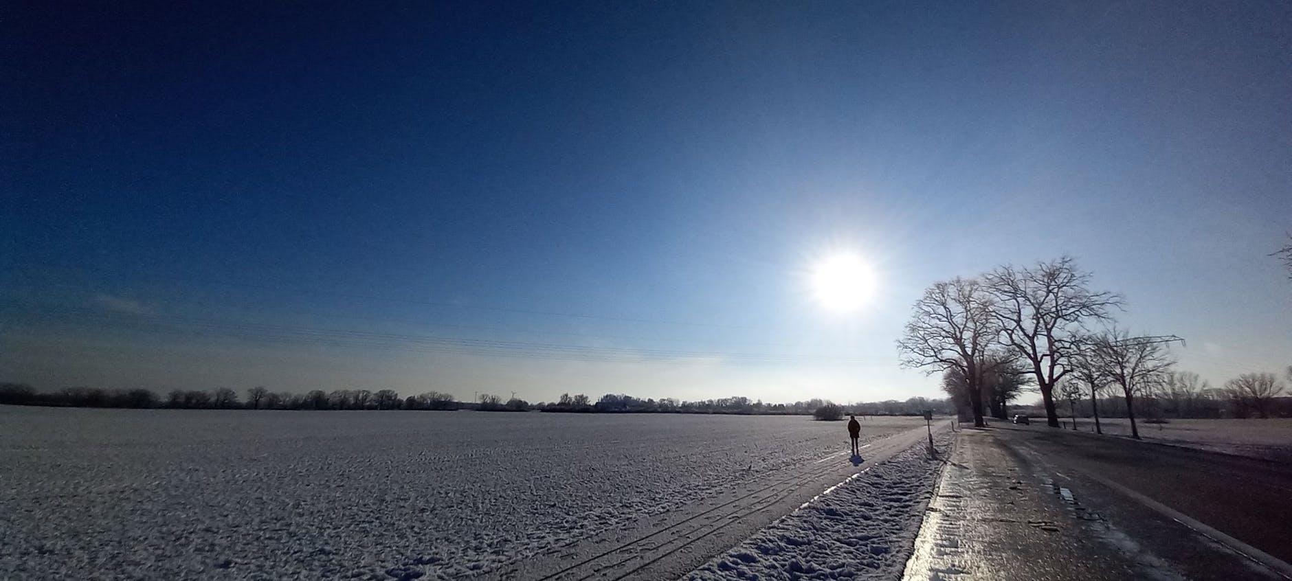 Eine Frau geht an einem schneebedeckten Acker vorbei.