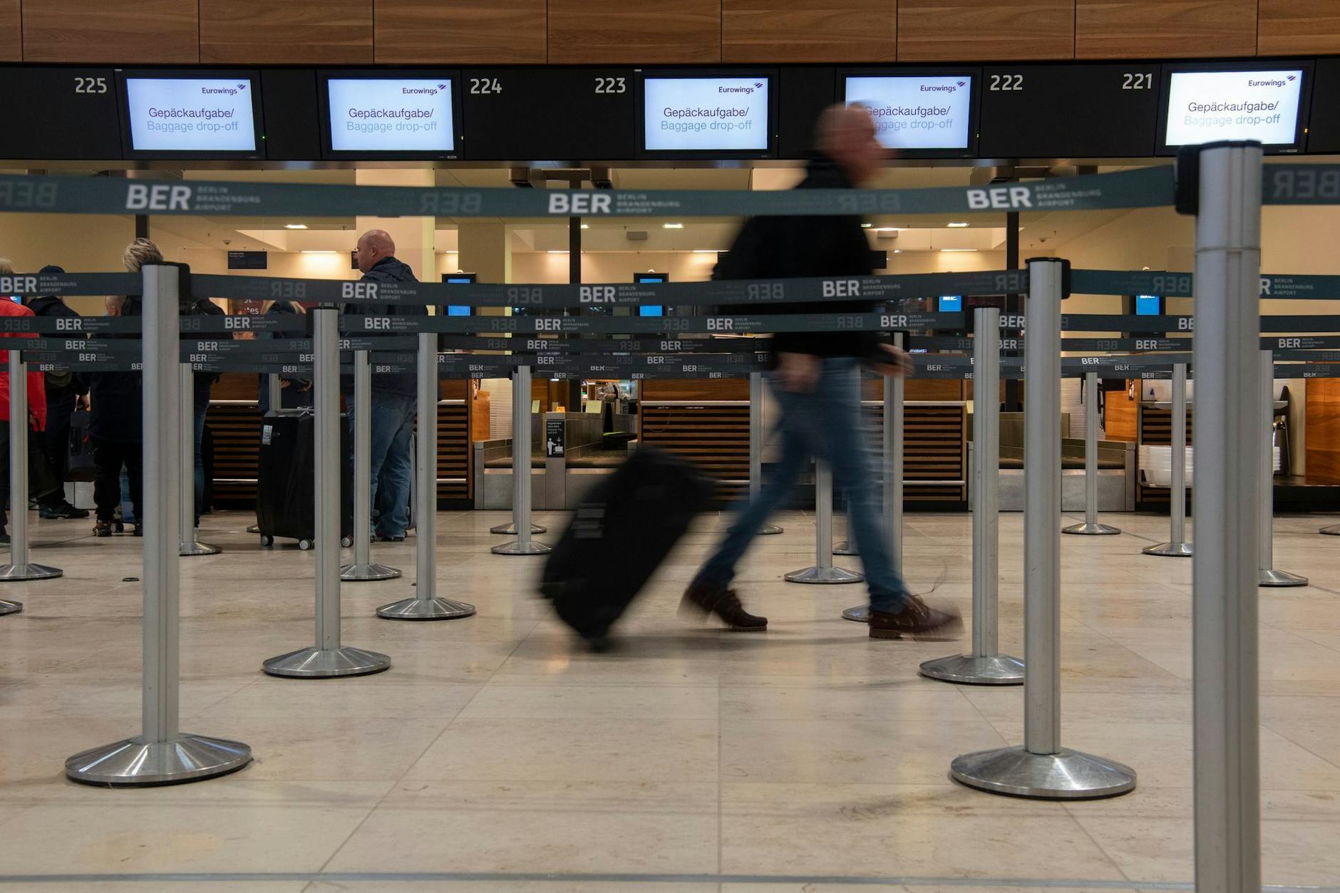 ARCHIV - Ein Reisender geht mit einem Koffer zu einem Check-in-Schalter von Eurowings.