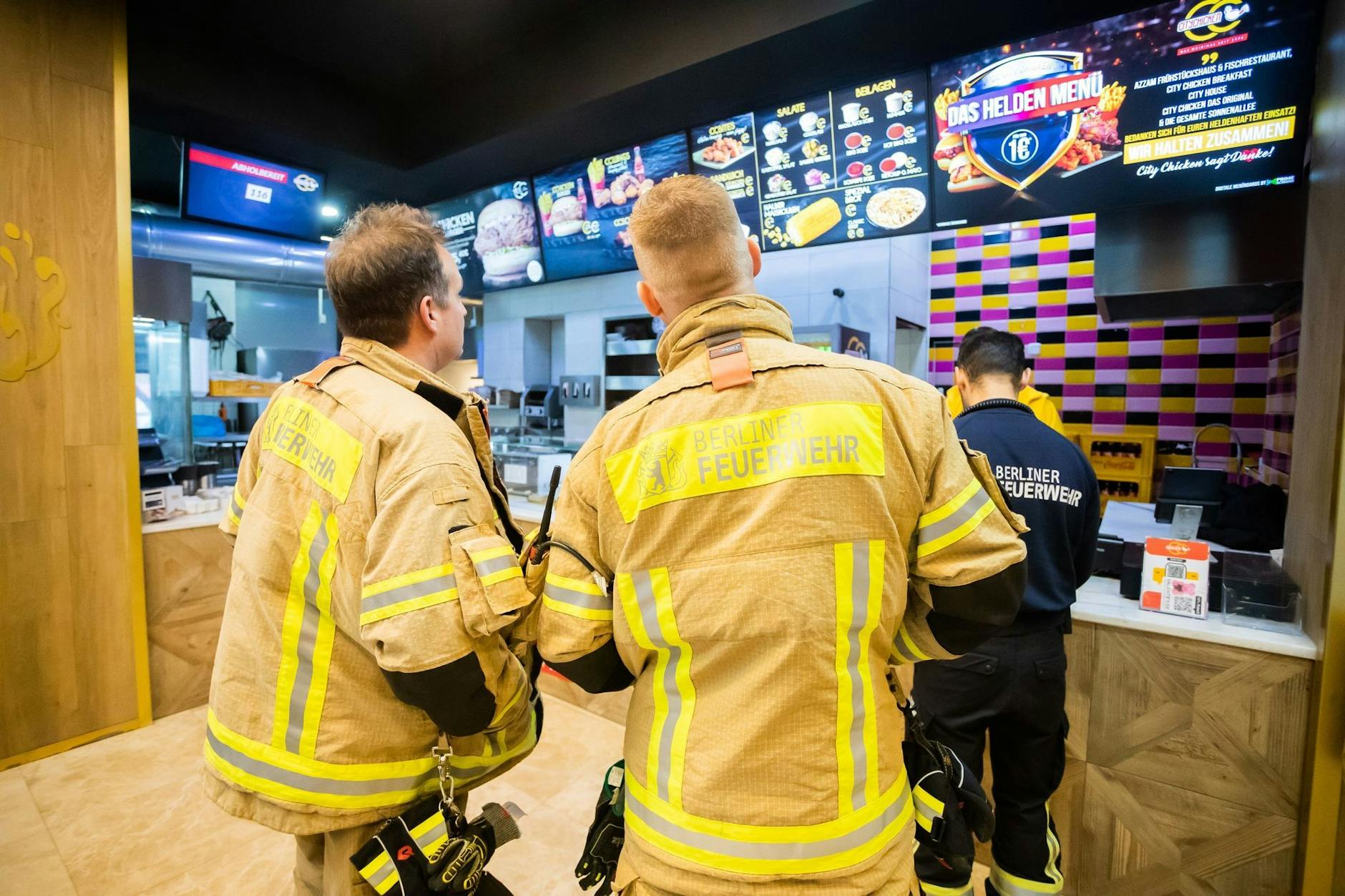 Feuerwehrleute bestellen im Restaurant «City Chicken das Original seit 1996» auf der Sonnenallee «Das Helden Menü».