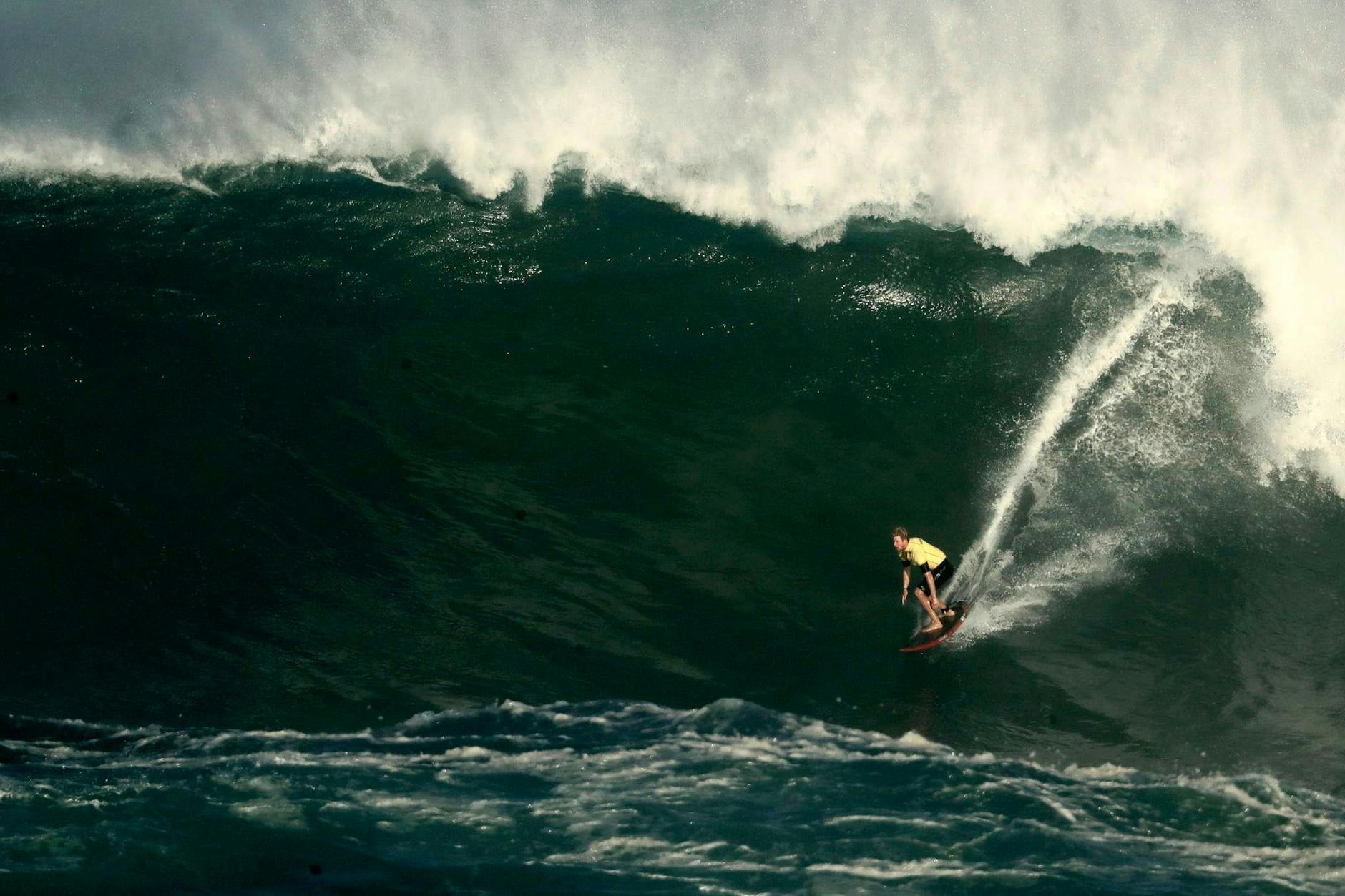 Ein Profisurfer reitet an Oahus North Shore in Hawaii beim Surfwettbewerb The Eddie auf einer Welle. iser via AP/dpa