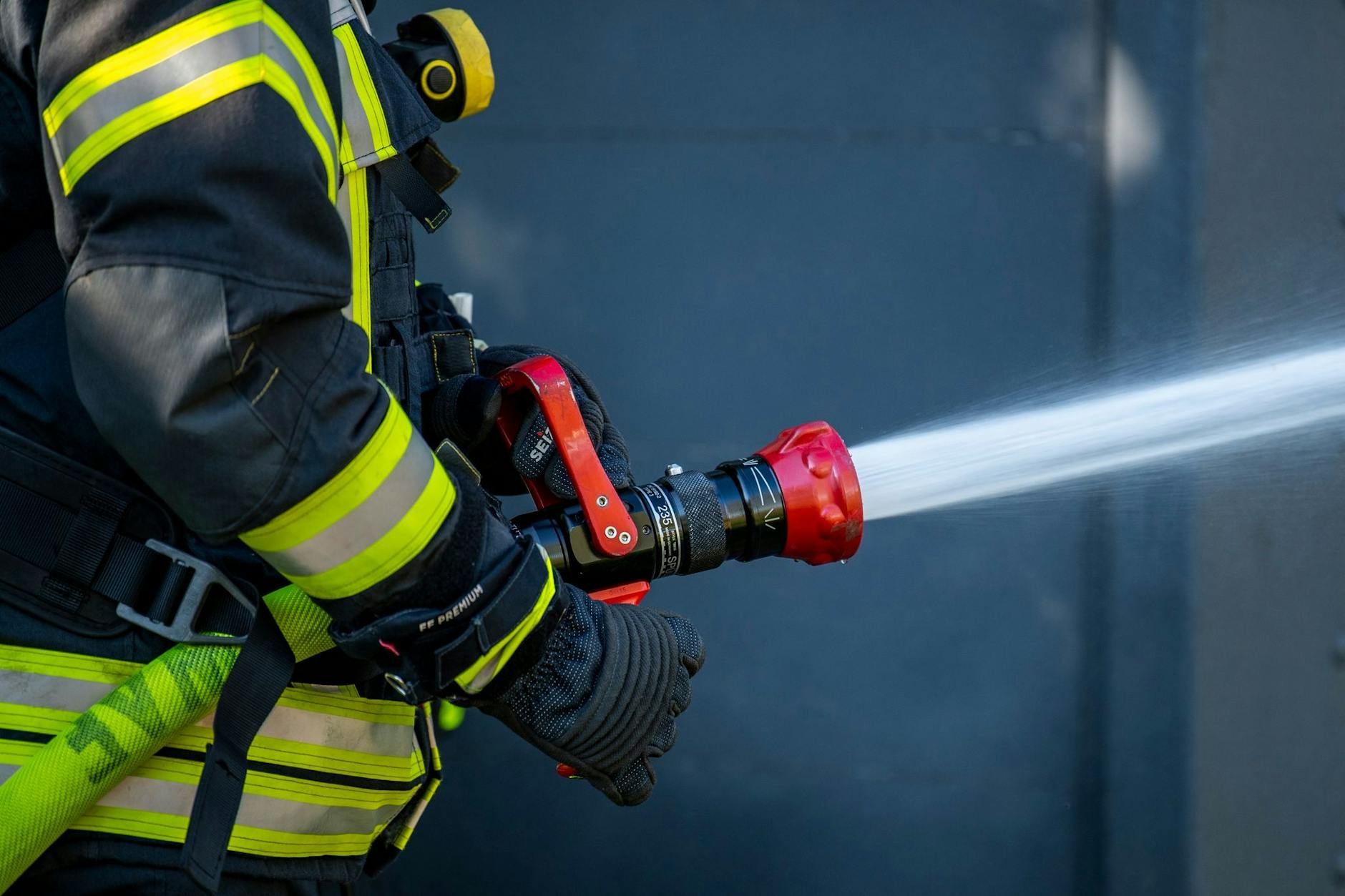PRODUKTION - Ein Mitglied der Feuerwehr spritzt aus einem Schlauch mit Wasser.