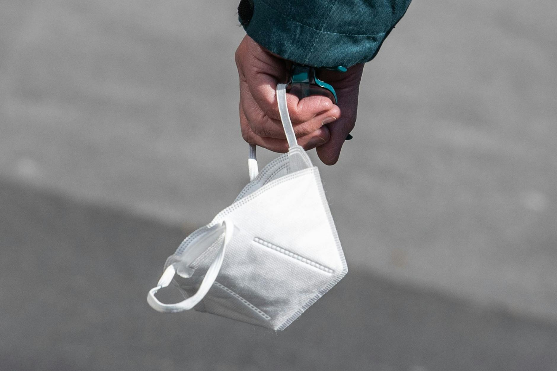 Ein Passant trägt eine FFP2-Maske in der Hand.