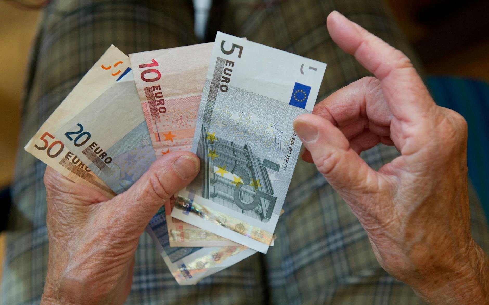 ARCHIV - Eine ältere Frau zählt Geld.