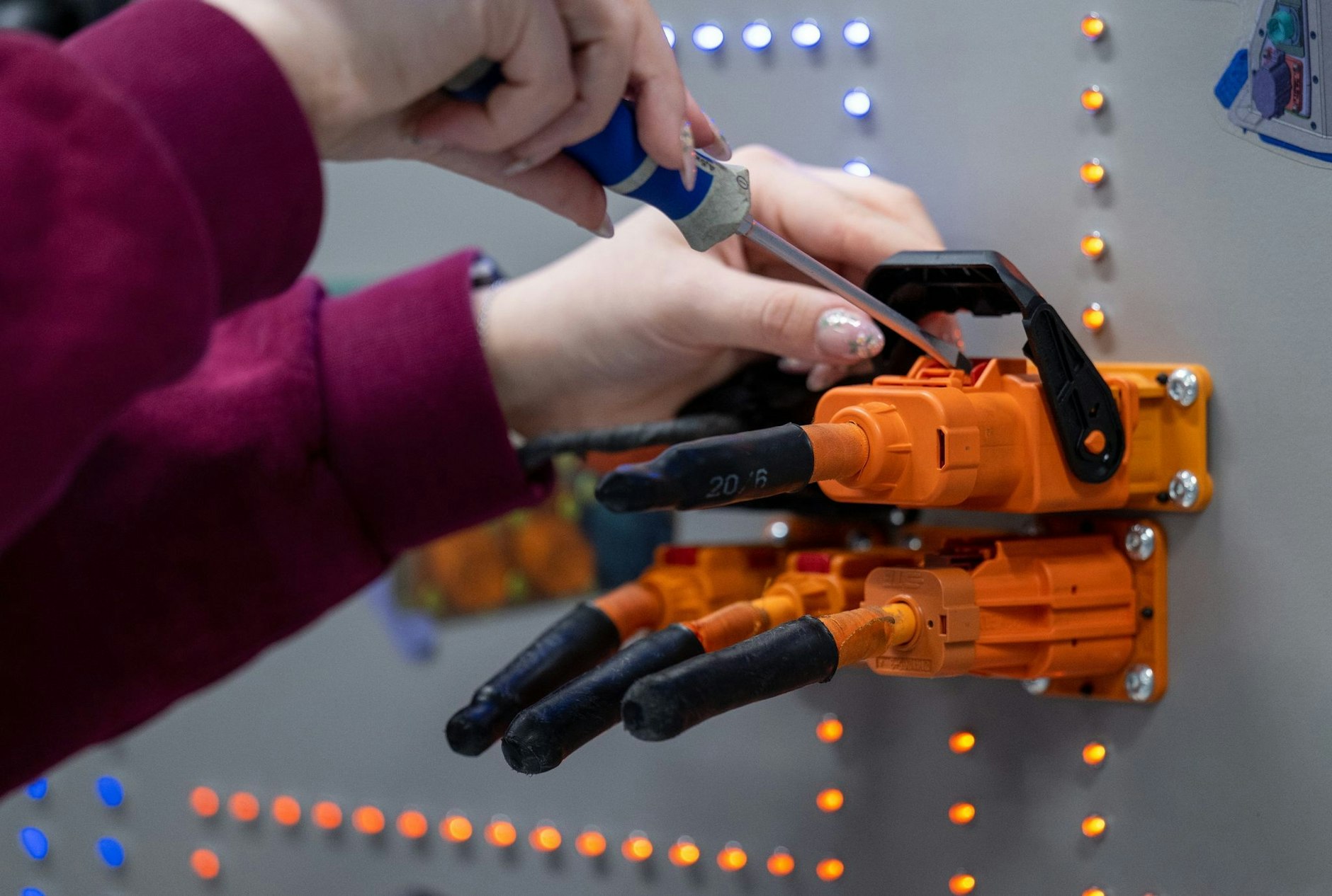 ARCHIV - Eine angehende KfZ-Mechatronikerin überprüft im Volkswagen Bildungsinstitut in Zwickau Stecker für ein Ladegerät.  