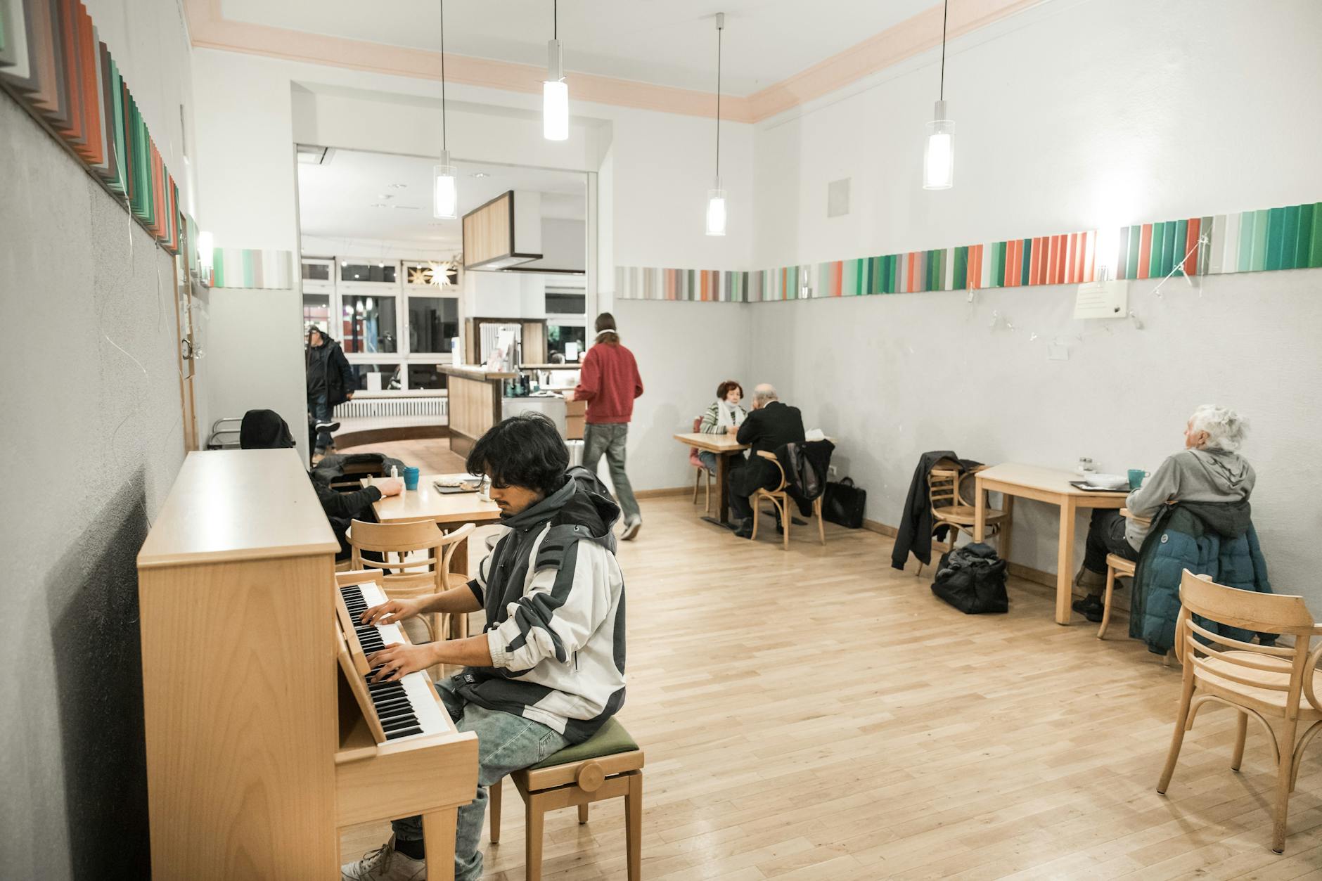 Ein Gast spielt Klavier, andere haben sich zum Kartenspielen zurückgezogen.