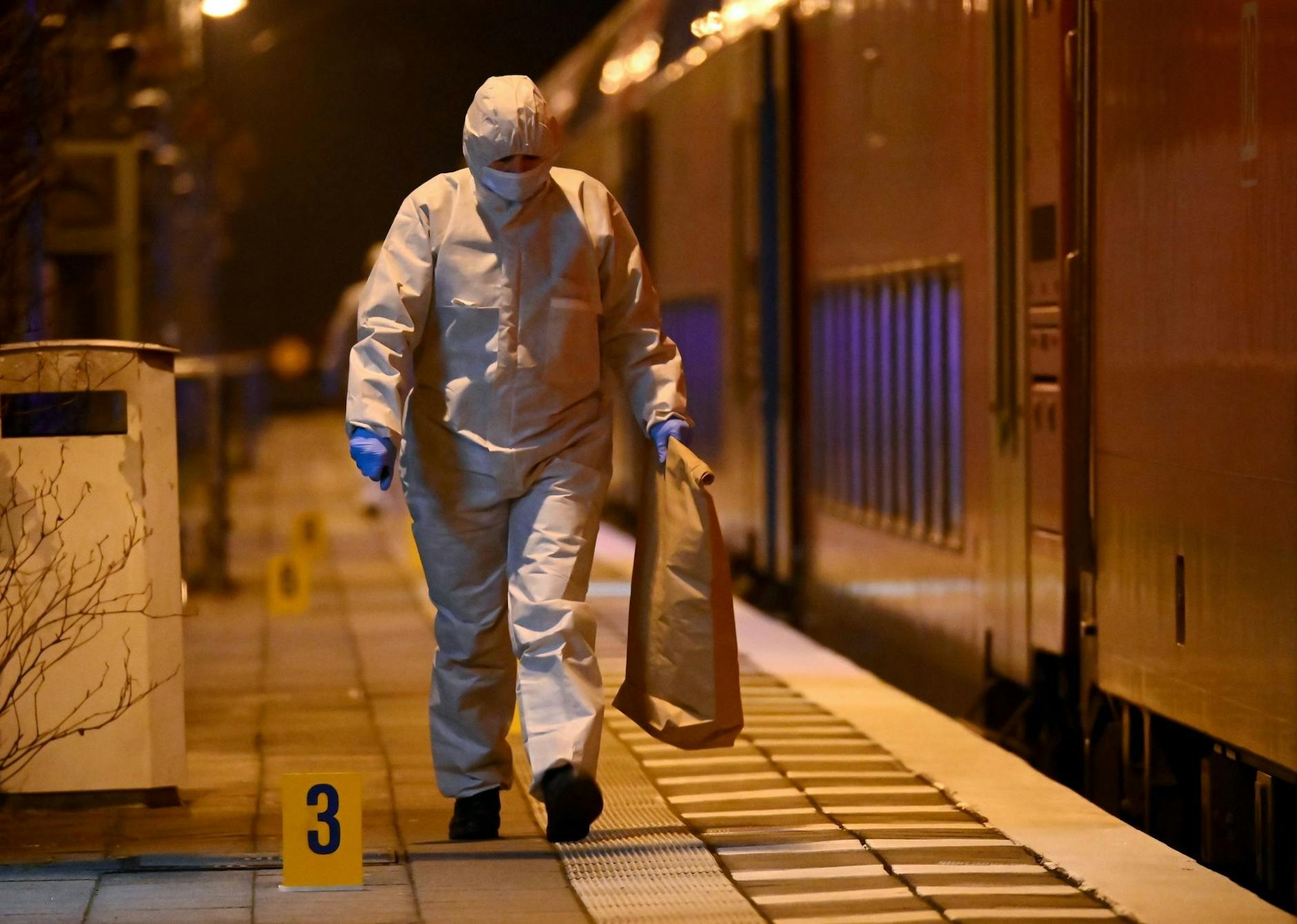 Mitarbeiter der Spurensicherung sind auf einem Bahnsteig bei einem Regionalzug im Einsatz.