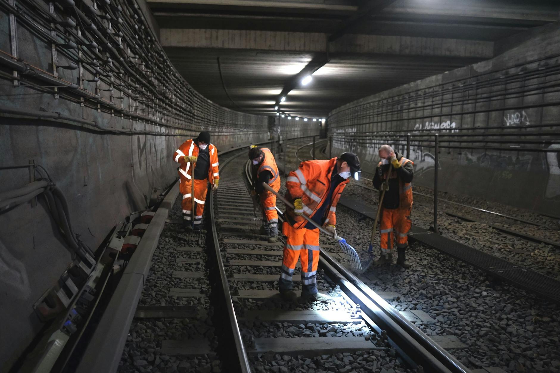 Der Nord-Süd-Tunnel der Berliner S-Bahn ist zur Baustelle geworden. Ein Bautrupp verteilt mit großen Gabeln den Schotter an einem Gleis unter der Spree.