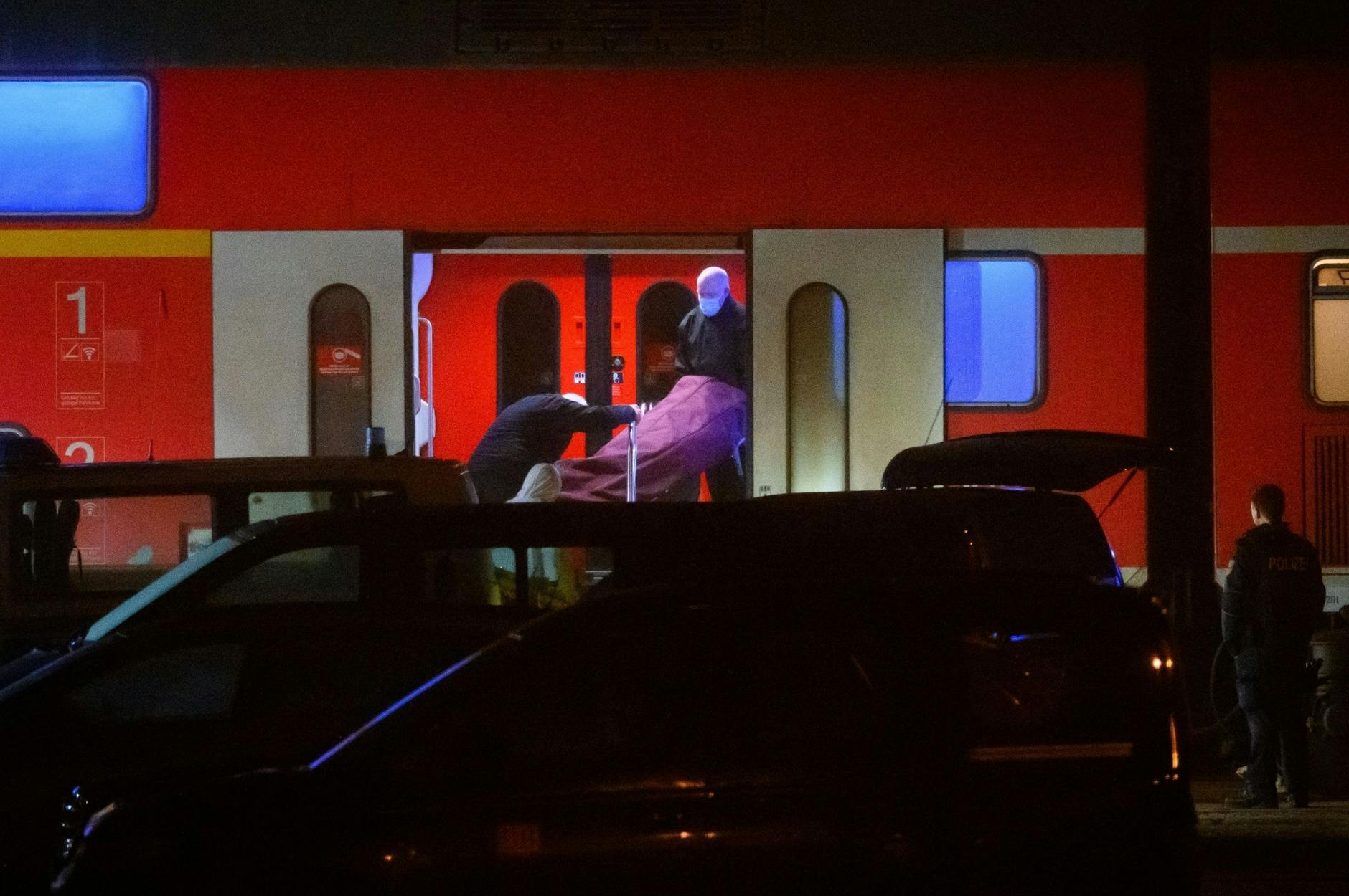 Bei der Messerattacke im Regionalzug wurden zwei Menschen getötet und mehrere verletzt. Bestatter tragen einen Leichnam aus dem Zug.