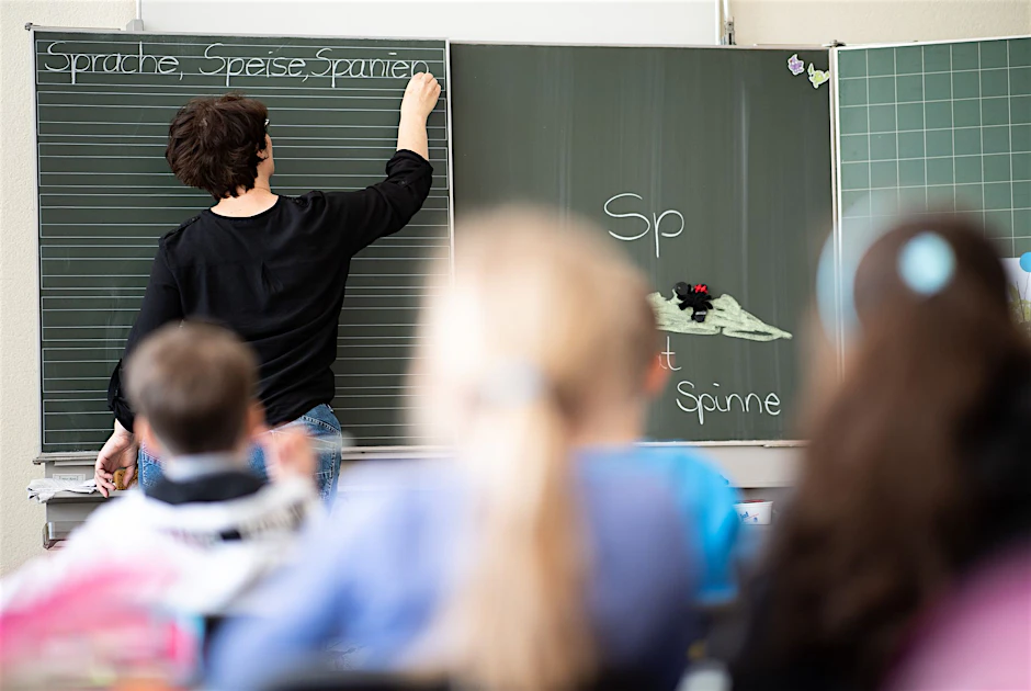 Eine Lehrerin schreibt in einer Grundschule Wörter an eine Tafel.