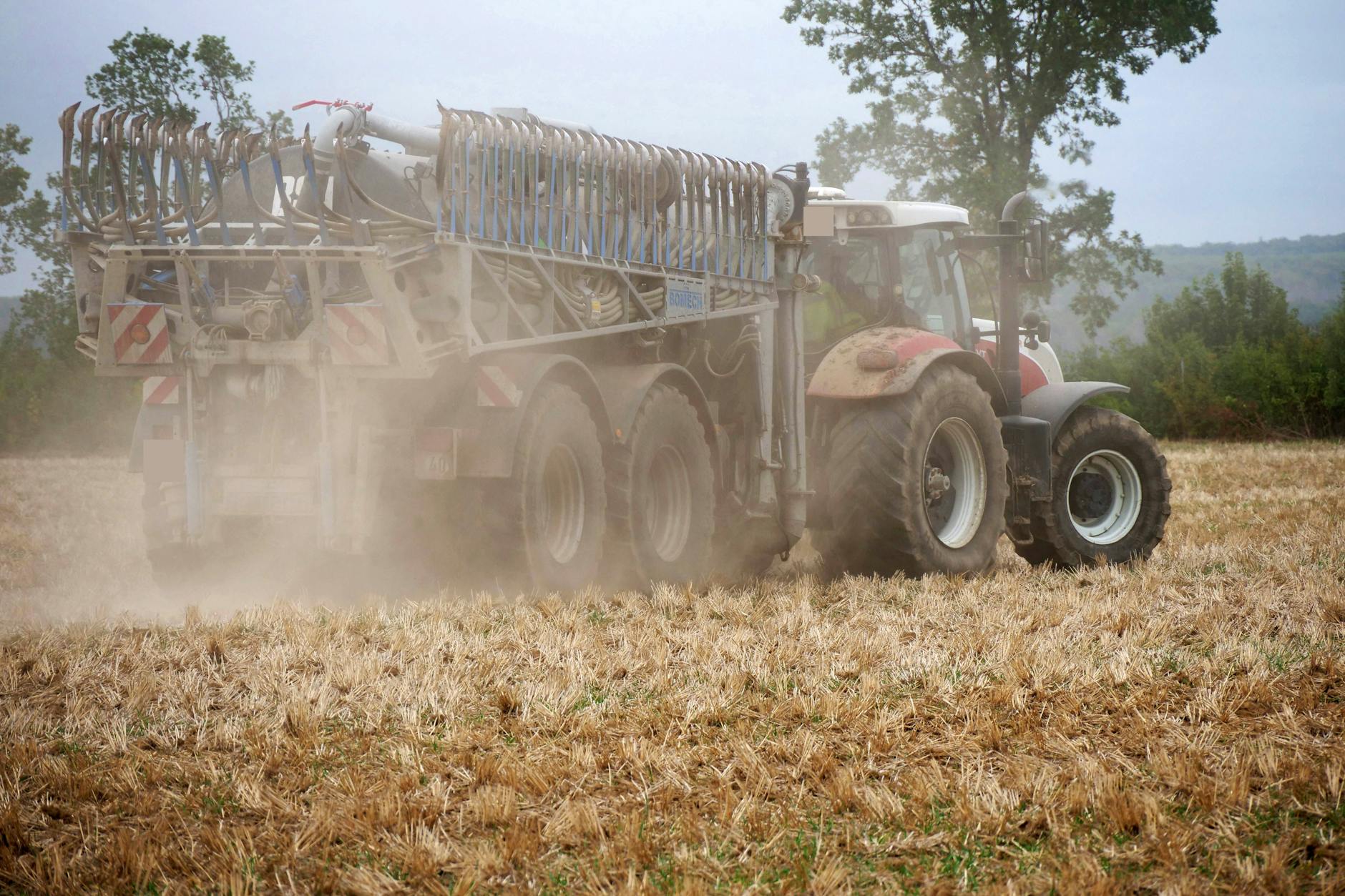 Ein Landwirt bringt per Güllefass mit Schleppschuh Gärsubstrat und Schweinegülle auf Ackerboden aus.
