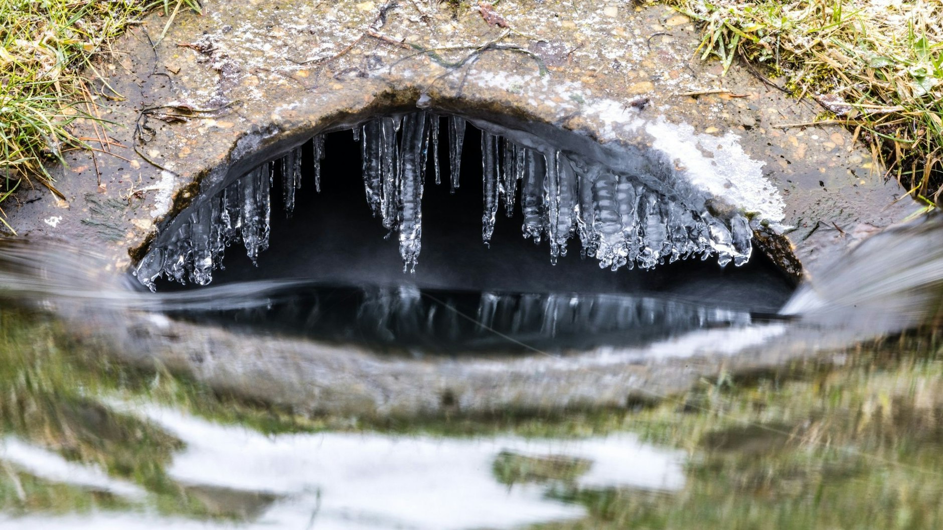 Wie ein Portal in die Unterwelt präsentiert sich ein Wassereinlauf mit kleinen Eiszapfen in Brandenburg. Es scheint fast so, als könnte man hier mit einem Boot zu einem fantastischen Abenteuer aufbrechen.  