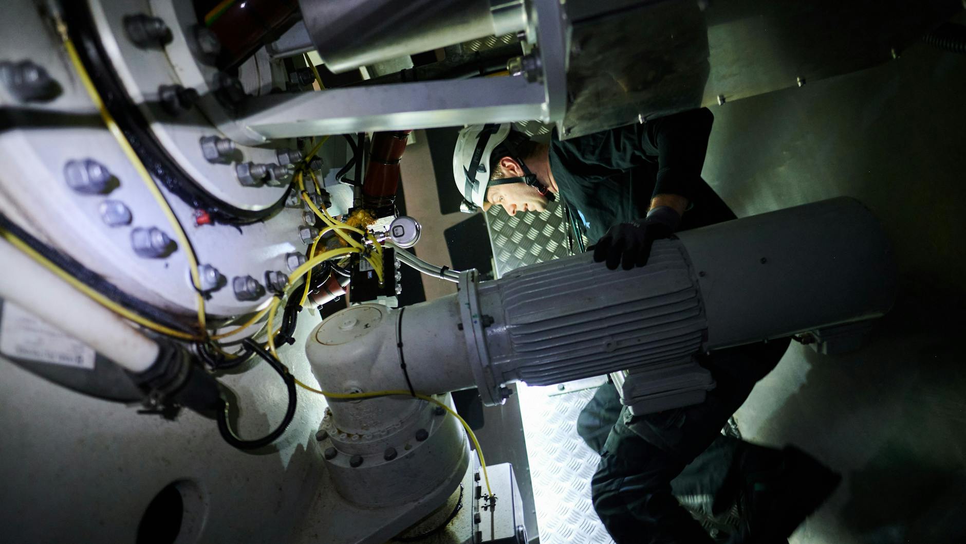 Jonas Knybba, Ingenieur und Betriebsführer bei Teut Windprojekte GmbH, führt mit einer Stirnlampe Sicherheitschecks in der Gondel eines Windrades in Pankow durch.