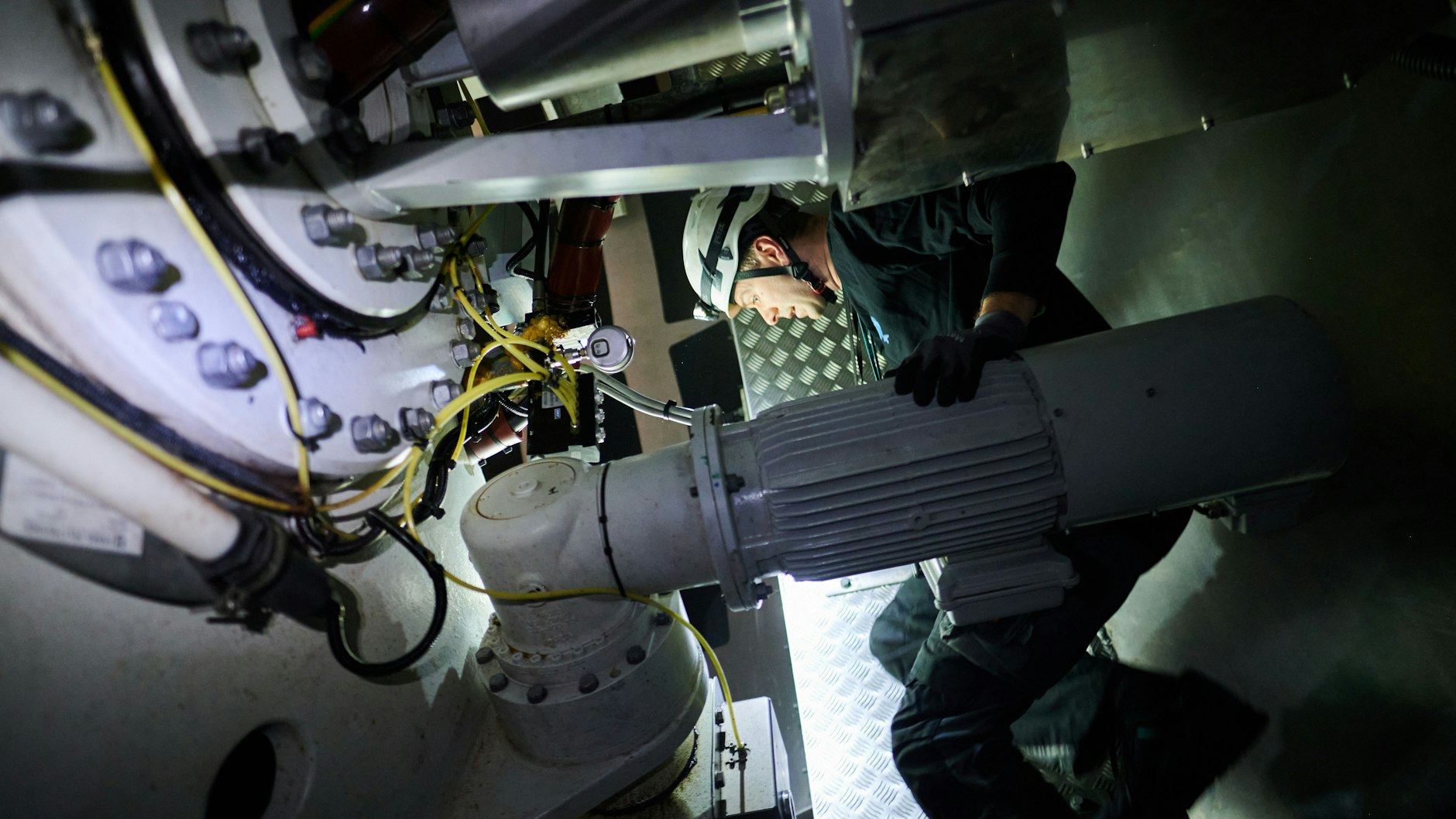 Jonas Knybba, Ingenieur und Betriebsführer bei Teut Windprojekte GmbH, führt mit einer Stirnlampe Sicherheitschecks in der Gondel eines Windrades in Pankow durch.