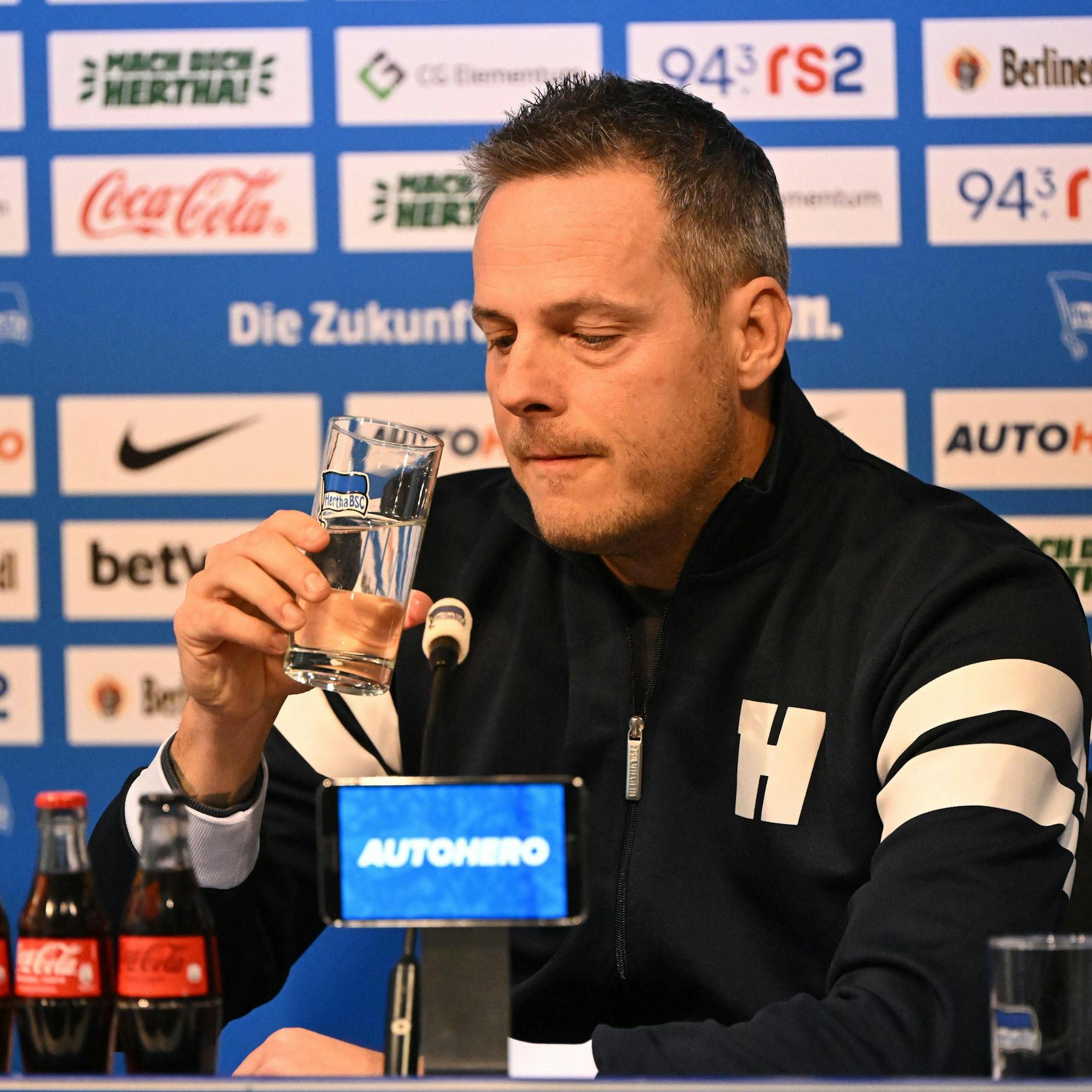Bernstein mit dunkelblauer Baseballjacke bei der Pressekonferenz. Nach der Begründung des Bobic-Rauschmisses nahm er erst mal einen Schluck Wasser.