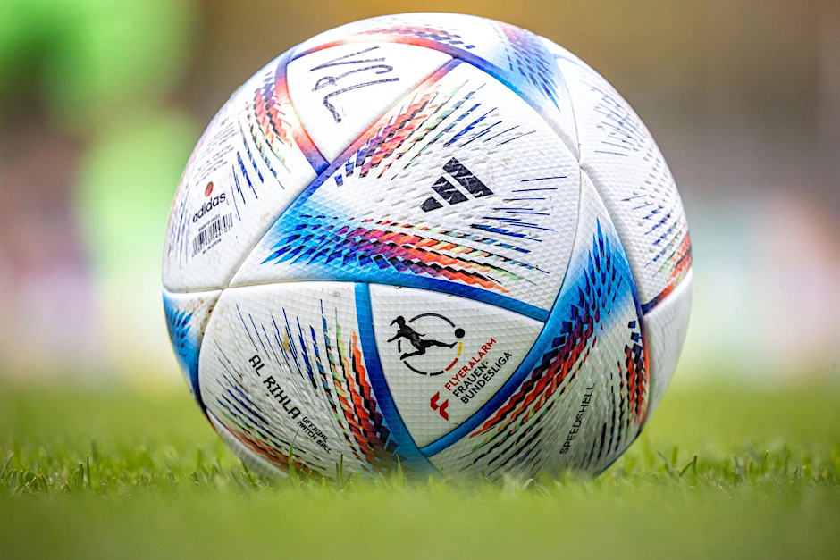 ARCHIV - Ein Fußball mit Schriftzug liegt auf dem Rasen bereit.  