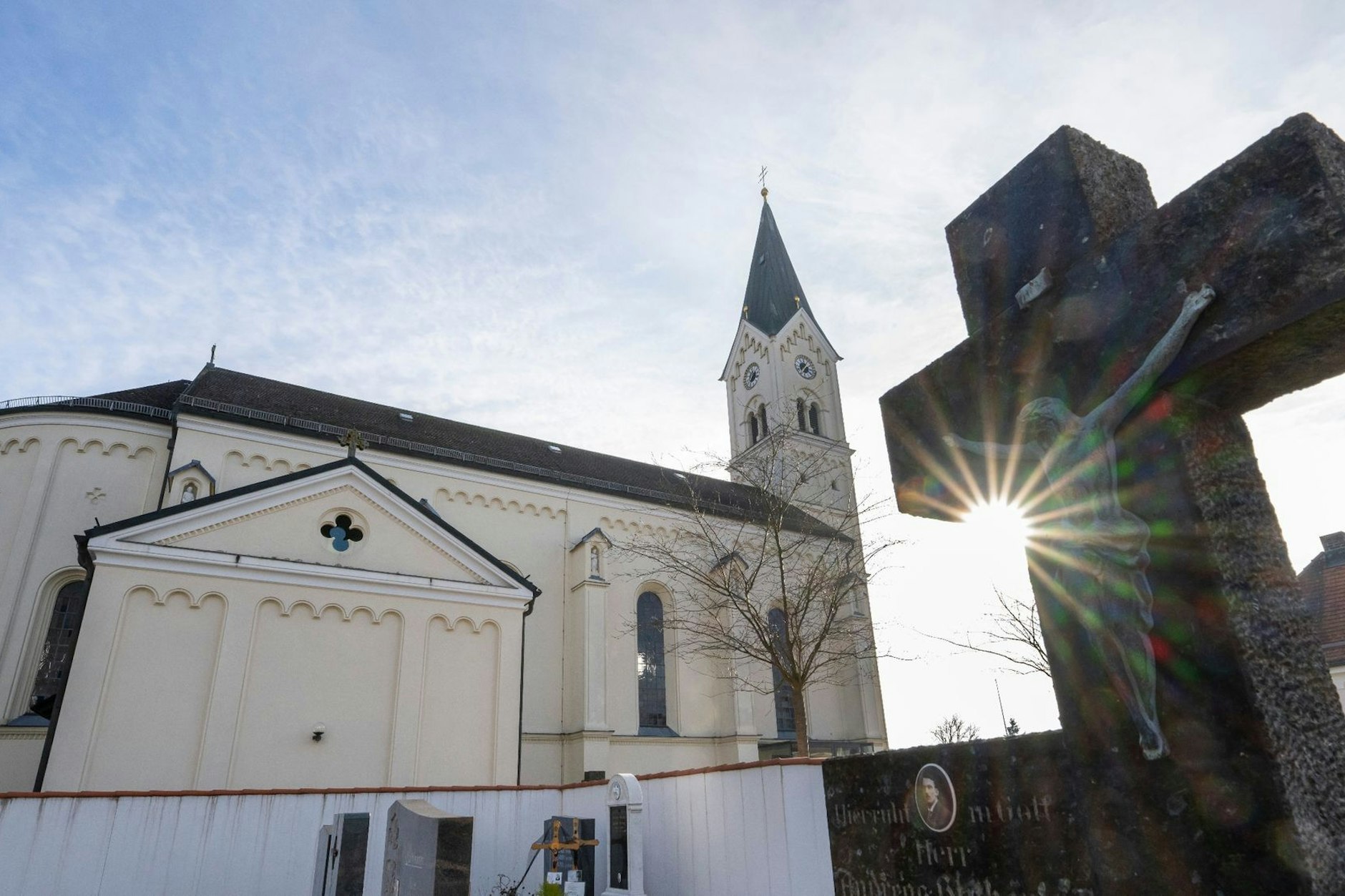Das Kreuz eines Grabsteins steht vor der katholische Kirche St. Nikolaus in Garching.