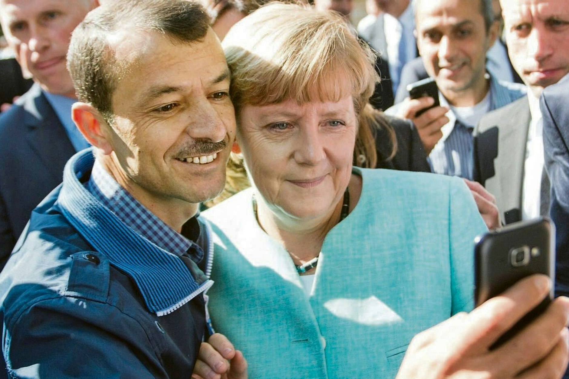 ARCHIV - 10.09.2015, Berlin: Bundeskanzlerin Angela Merkel (CDU) lässt sich nach dem Besuch einer Erstaufnahmeeinrichtung für Asylbewerber für ein Selfie zusammen mit Shaker Kedida aus Mossul (Irak) fotografieren.