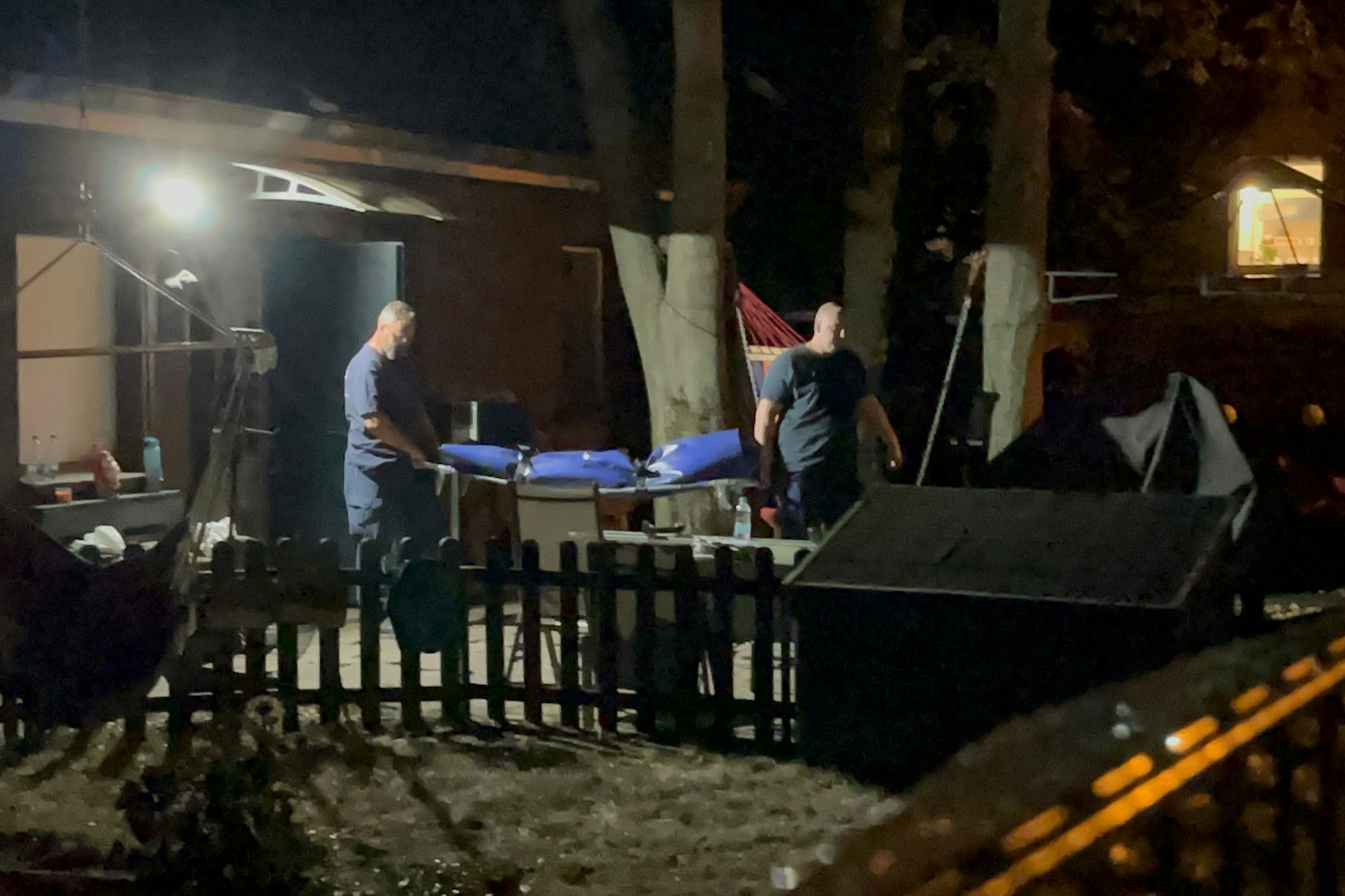 Mitarbeiter der Gerichtsmedizin tragen eine Bahre mit der toten jungen Frau aus dem Haus der Pflegerin. 