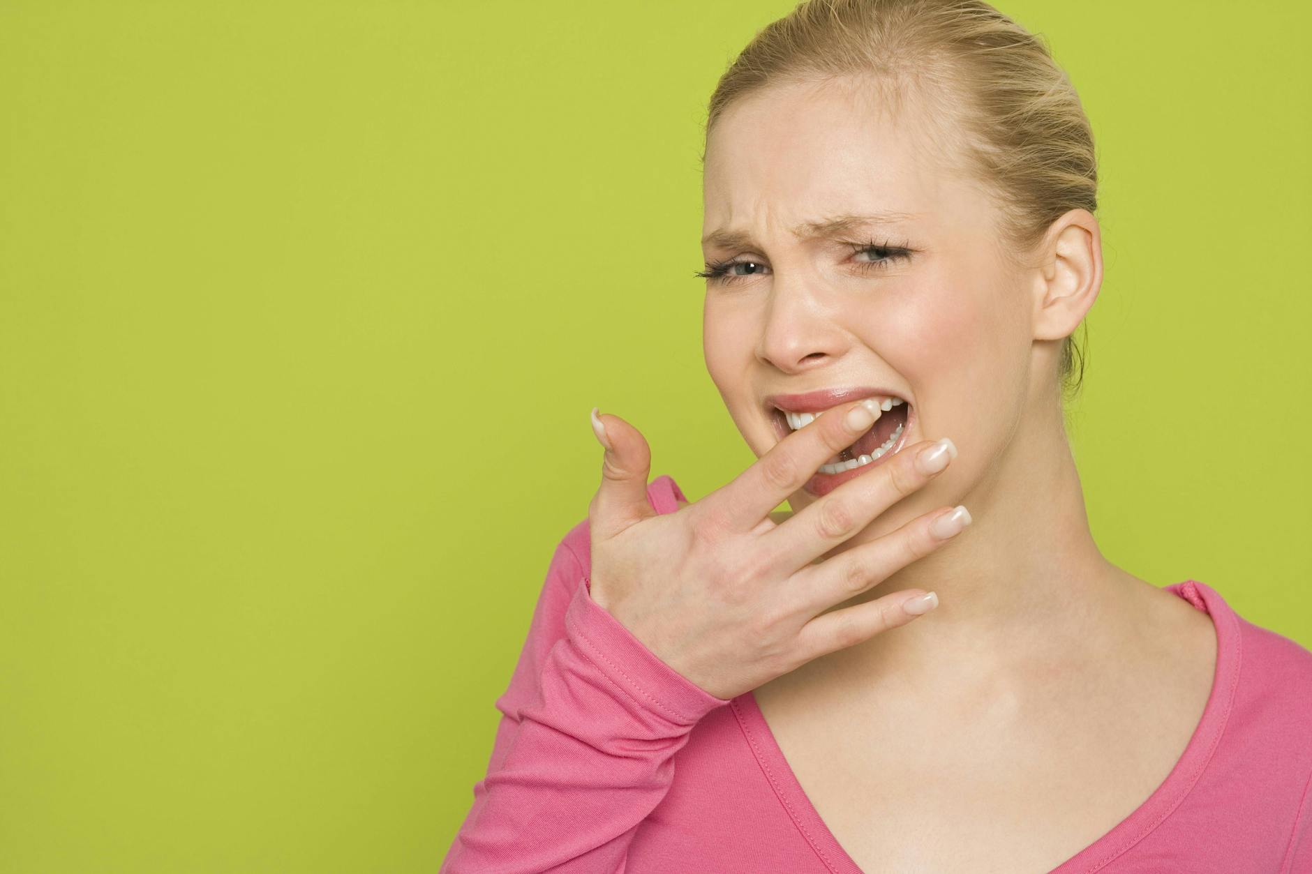 Ein Frau fasst sich in den Mund: Es ist die Geste zum 9. Februar, dem Tag des Zahnschmerzes.