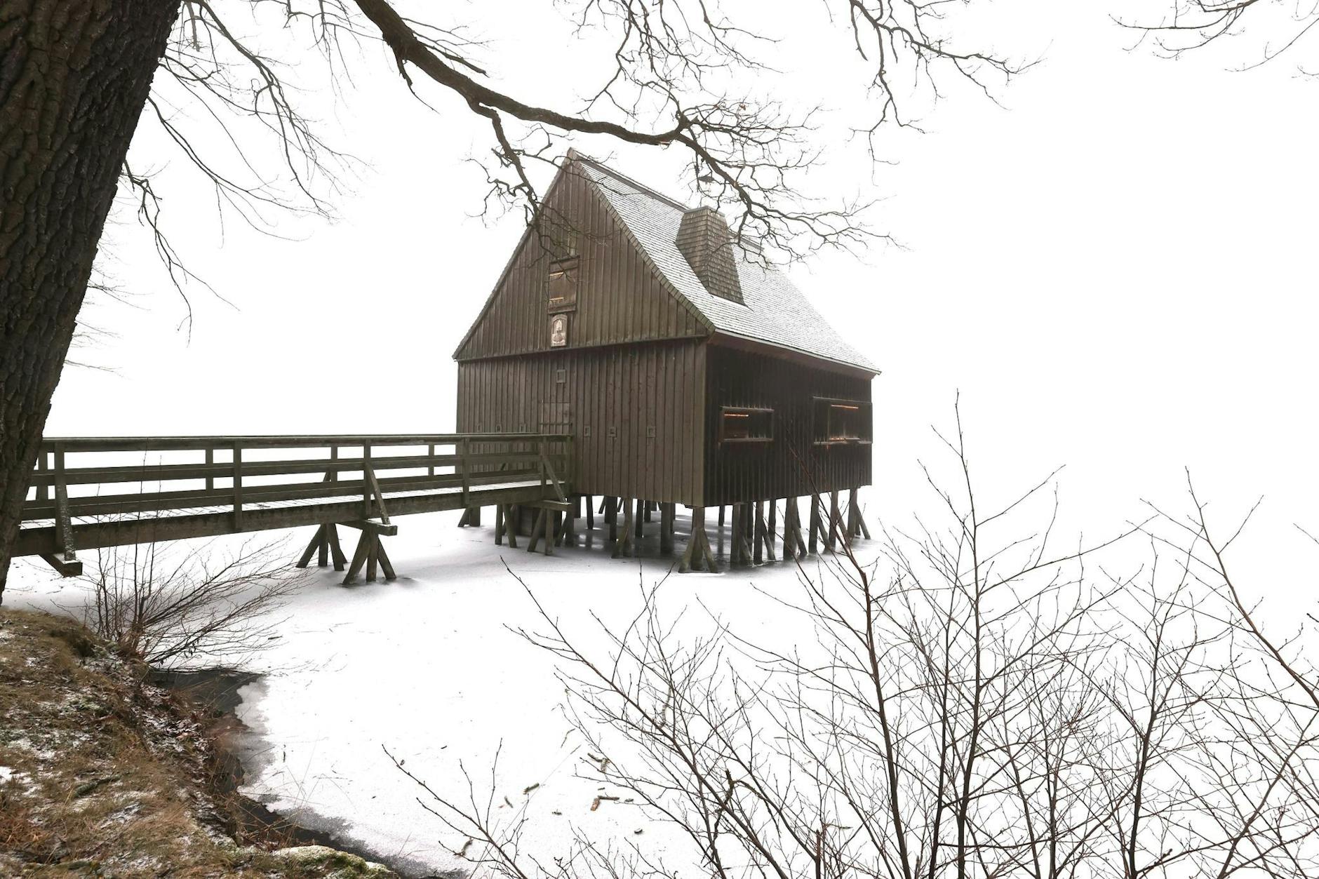 Ein Pfahlhaus steht im zugefrorenen Wasser eines Teiches des Plothener Teichgebietes in Thüringen.