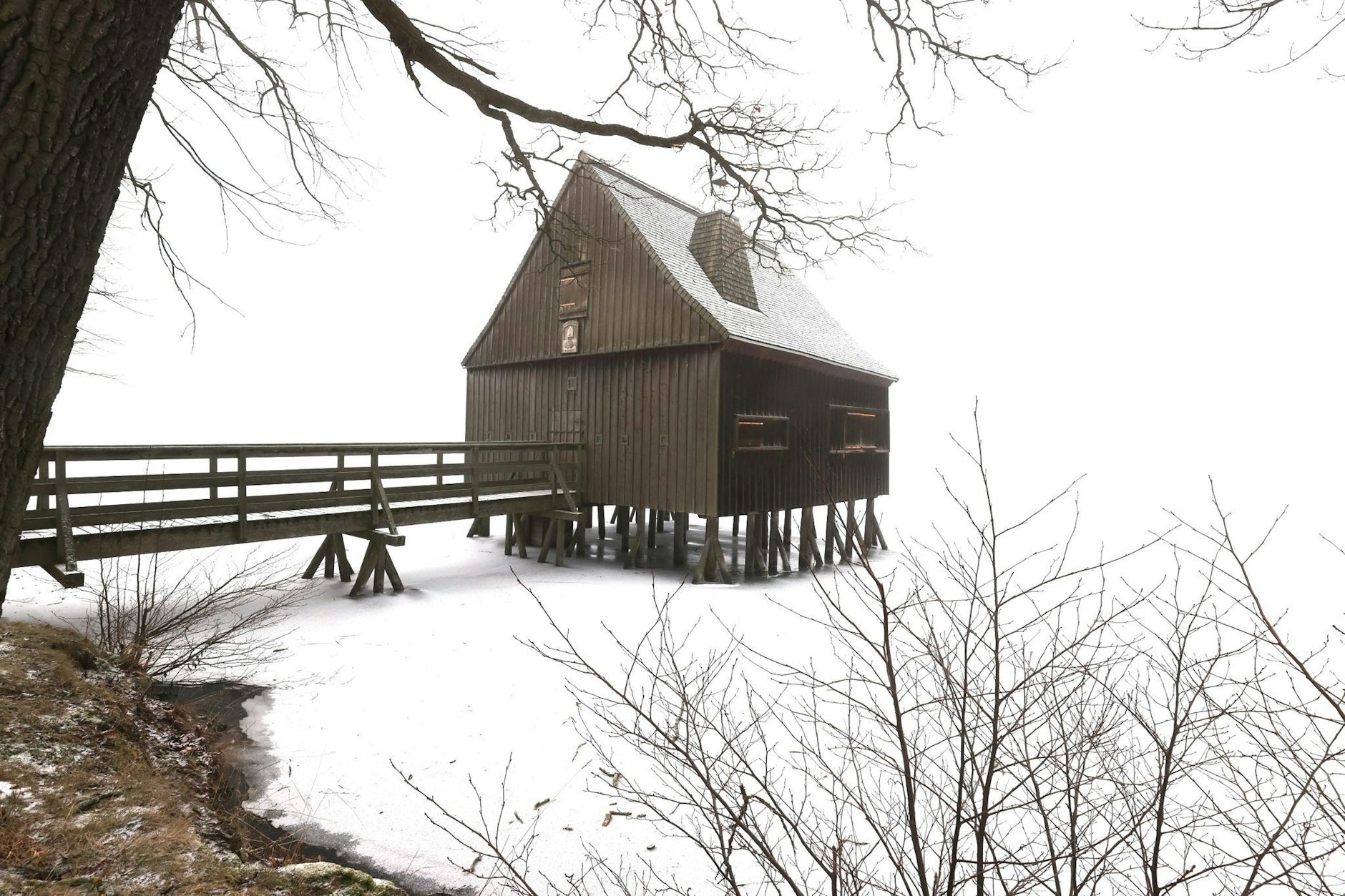 Ein Pfahlhaus steht im zugefrorenen Wasser eines Teiches des Plothener Teichgebietes in Thüringen.  