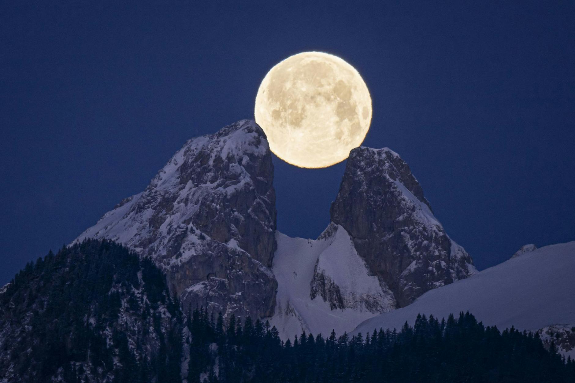 Der Vollmond geht von Aigle im Schweizer Kanton Waadt aus gesehen hinter den Bergen unter, darunter die Zwillingsgipfel von Les Jumelles im Chablais Valaisan.