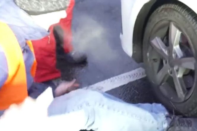 Ein Autofahrer fährt am Montagmorgen am Messedamm über den Fuß eines Aktivisten. 