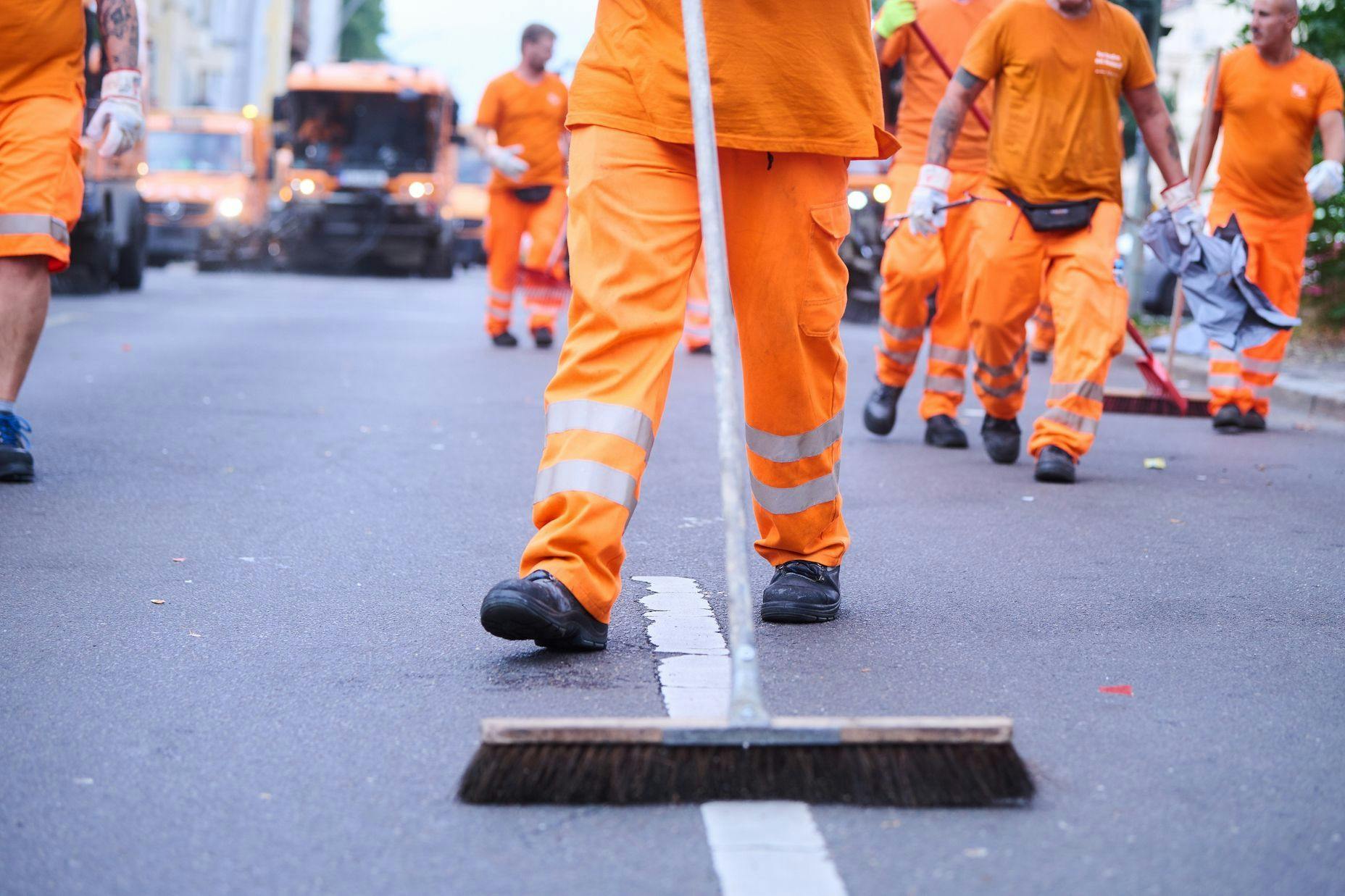 Mitarbeiter der Berliner Stadtreinigung (BSR) und Putzfahrzeuge reinigen die Straße. Am Donnerstag kommt es zu einem Warnstreik.
