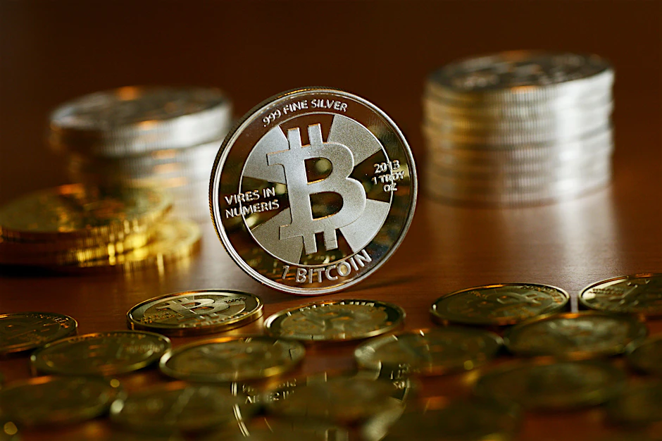 Münzen mit dem Aufdruck „Bitcoin“ stehen und liegen auf einem Tisch (Symbolbild).