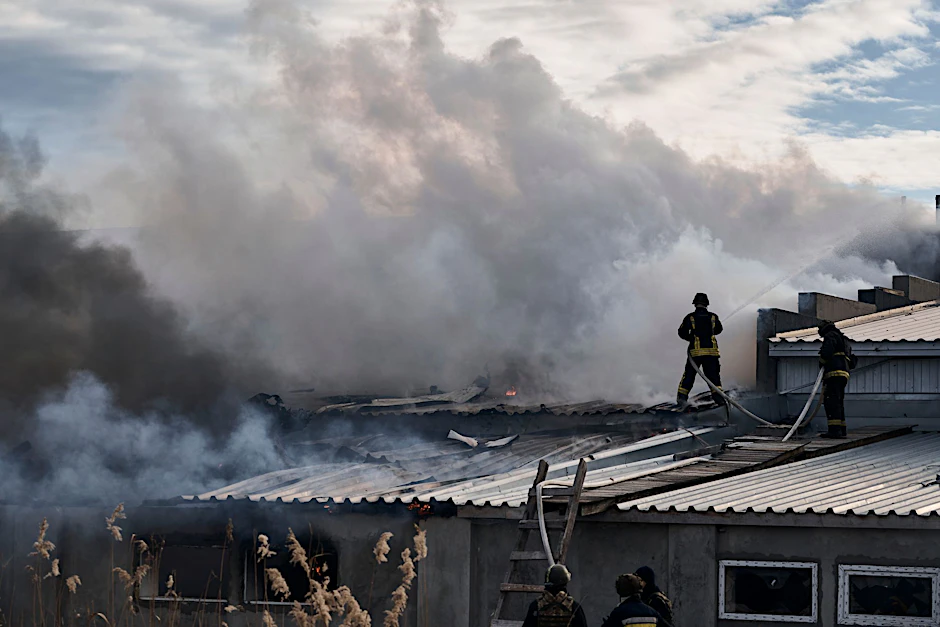 Feuerwehrleute des staatlichen ukrainischen Katastrophenschutzes löschen ein Feuer, das nach Beschuss eines Industriegebiets in Cherson ausgebrochen ist.