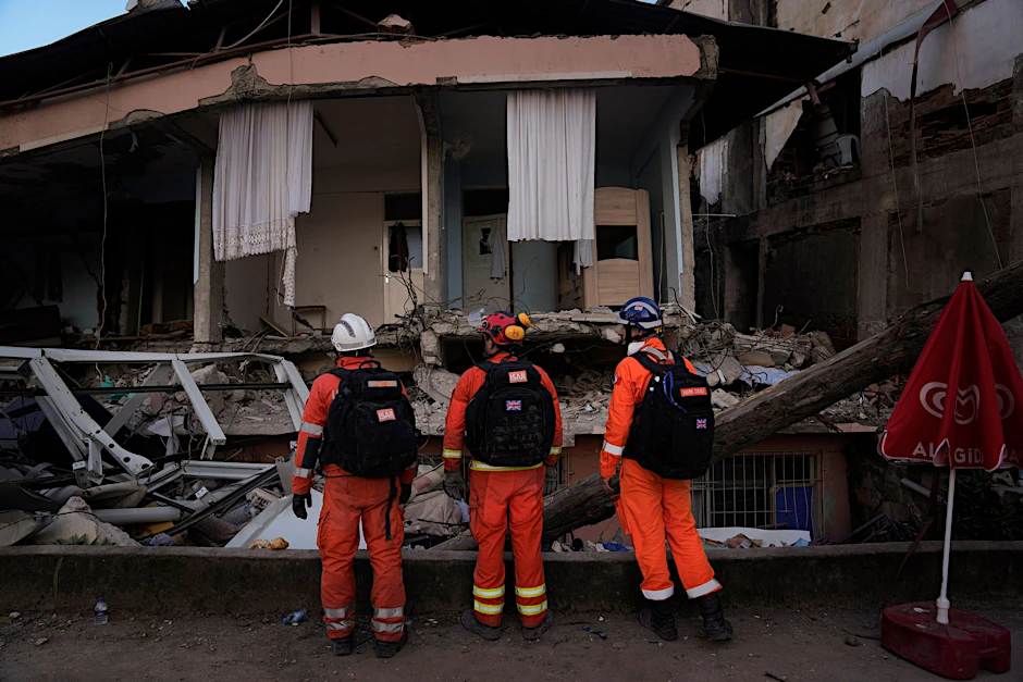 Helfer im türkischen Antakya vor einem zerstörten Haus