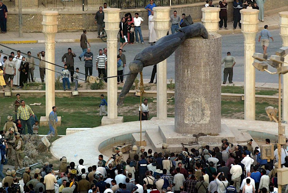 Iraker sehen zu, wie eine Statue des irakischen Präsidenten Saddam Hussein auf dem al-Fardous-Platz (Paradies) in Bagdad am 09. April 2003 fällt.