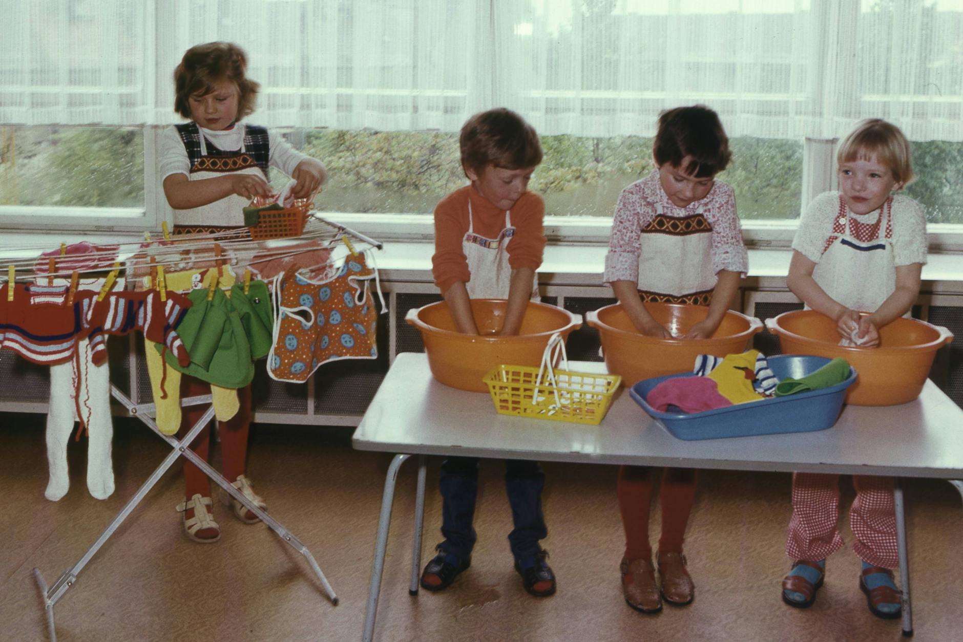 1976 in der DDR: Kindergartenkinder waschen Kleidungsstücke per Hand.