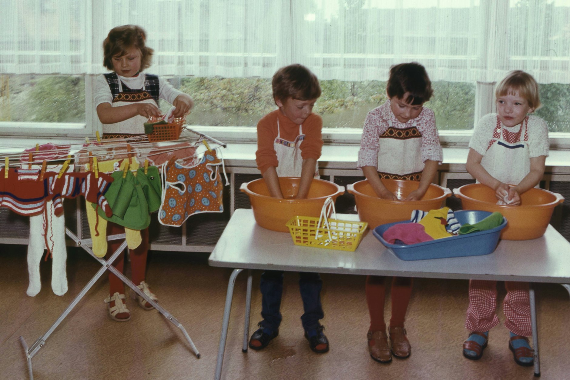 1976 in der DDR: Kindergartenkinder waschen Kleidungsstücke per Hand. 