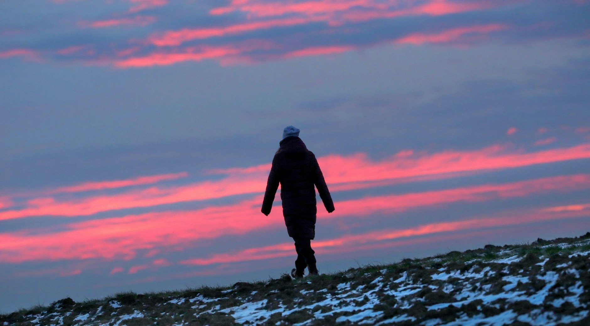 Bei Minusgraden unterwegs auf einem Feldweg im baden-württembergischen Uttenweiler. Im Hintergrund verfärben sich am Horizont kurz vor Sonnenaufgang die Wolken rötlich.  
