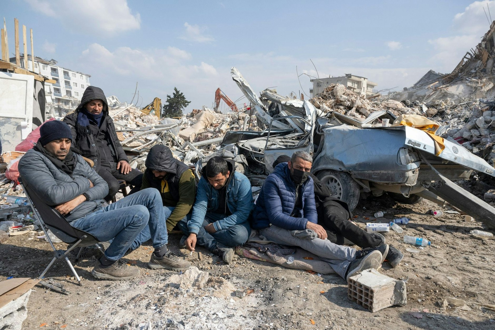 Junge Helfer sitzen in Antakya erschöpft zwischen den Trümmern.  