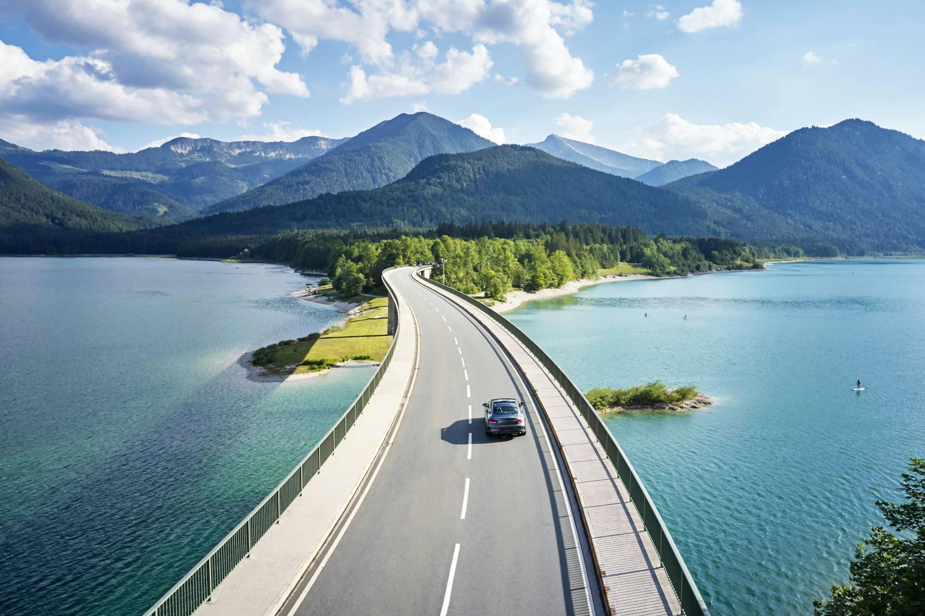 Mit dem Auto lassen sich ferne Orte entdecken. Stausee Sylvenstein, Bayern.