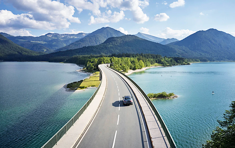 Mit dem Auto lassen sich ferne Orte entdecken. Stausee Sylvenstein, Bayern.