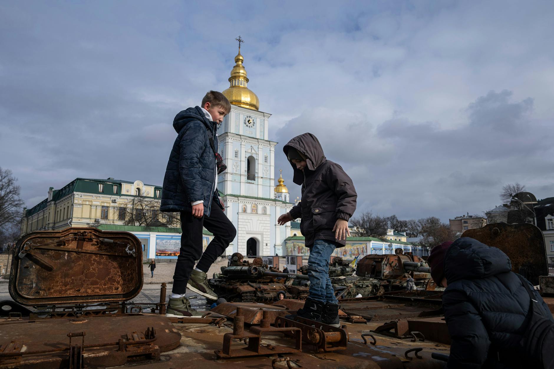 Kinder stehen auf einem zerstörten russischen Fahrzeug im Stadtzentrum von Kiew. Einer US-Studie zufolge wurden tausende ukrainische Kinder von Russland verschleppt.