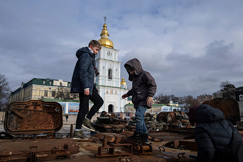 Kinder stehen auf einem zerstörten russischen Fahrzeug im Stadtzentrum von Kiew. Einer US-Studie zufolge wurden tausende ukrainische Kinder von Russland verschleppt.