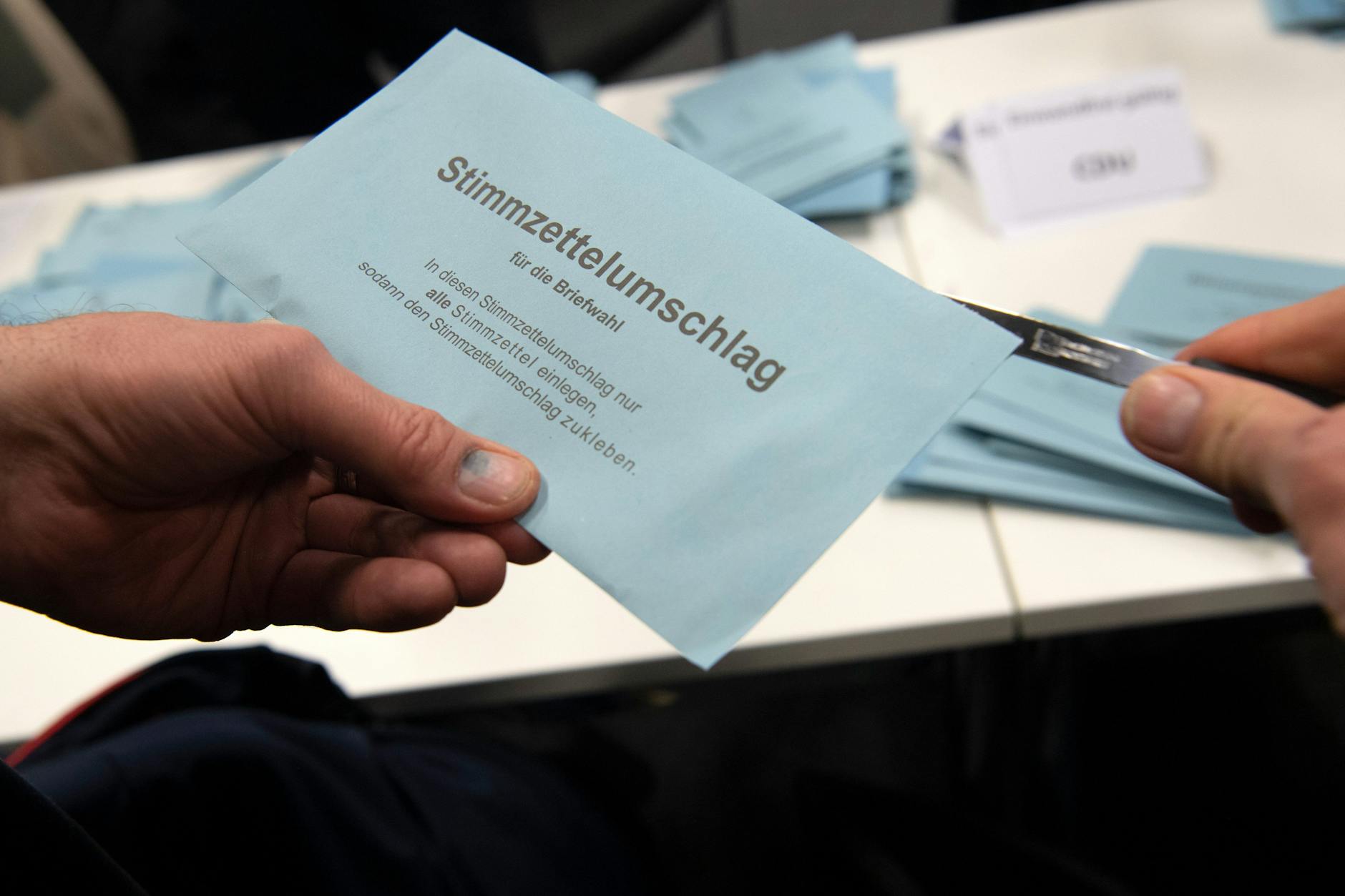 Ein Wahlhelfer öffnet im City Cube nach der wiederholten Wahl den Stimmzettelumschlag eines Briefwählers.