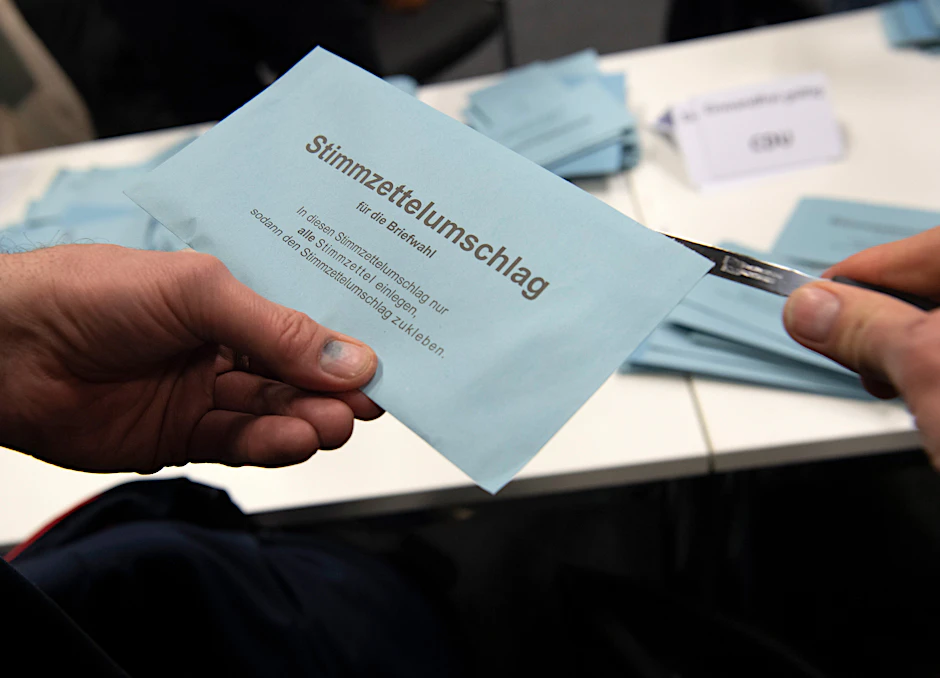 Ein Wahlhelfer öffnet im City Cube nach der wiederholten Wahl den Stimmzettelumschlag eines Briefwählers.