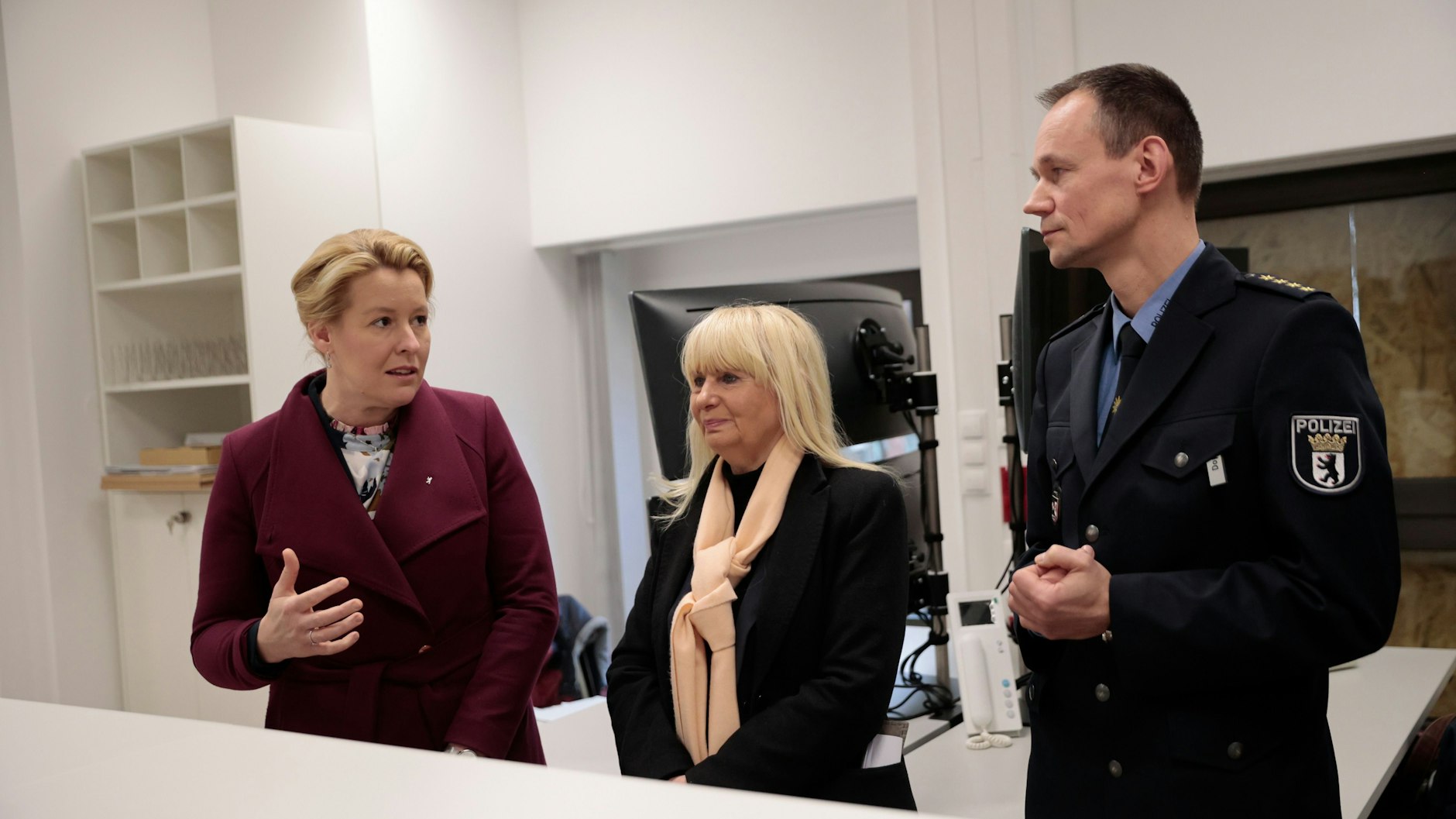 Franziska Giffey (l.) spricht mit Iris Spranger und Steffen Dopichay (r.), Leiter der Polizeidirektion, am Empfangstresen bei einem Besuch der neuen Polizeiwache am Kottbusser Tor.