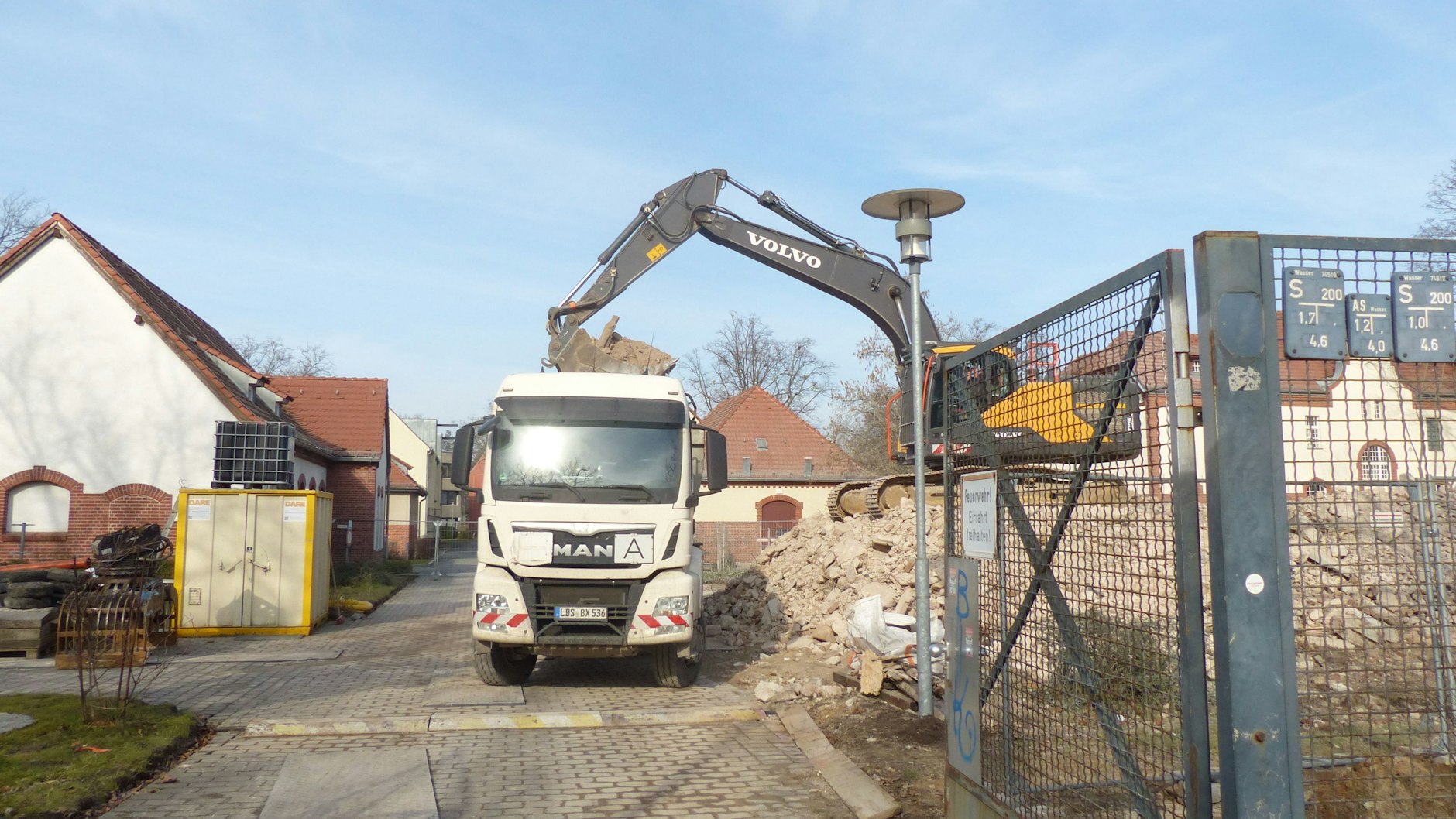 Gegenwärtig werden Lkw mit dem Schutt des abgerissenen Gebäudes beladen.