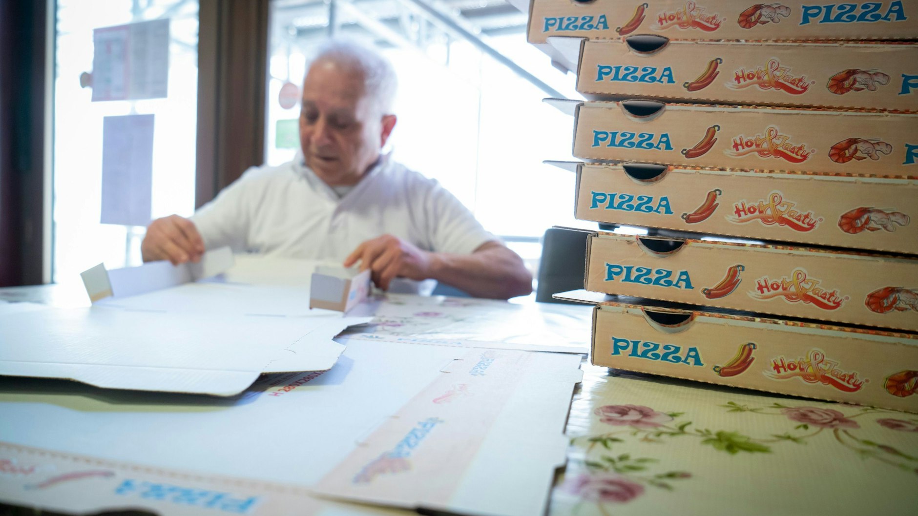 Pizzabäcker Juiseppe Pepe mit einem Stapel Pizzakartons in seiner Pizzeria „Pepe“ in Frankfurt am Main. 