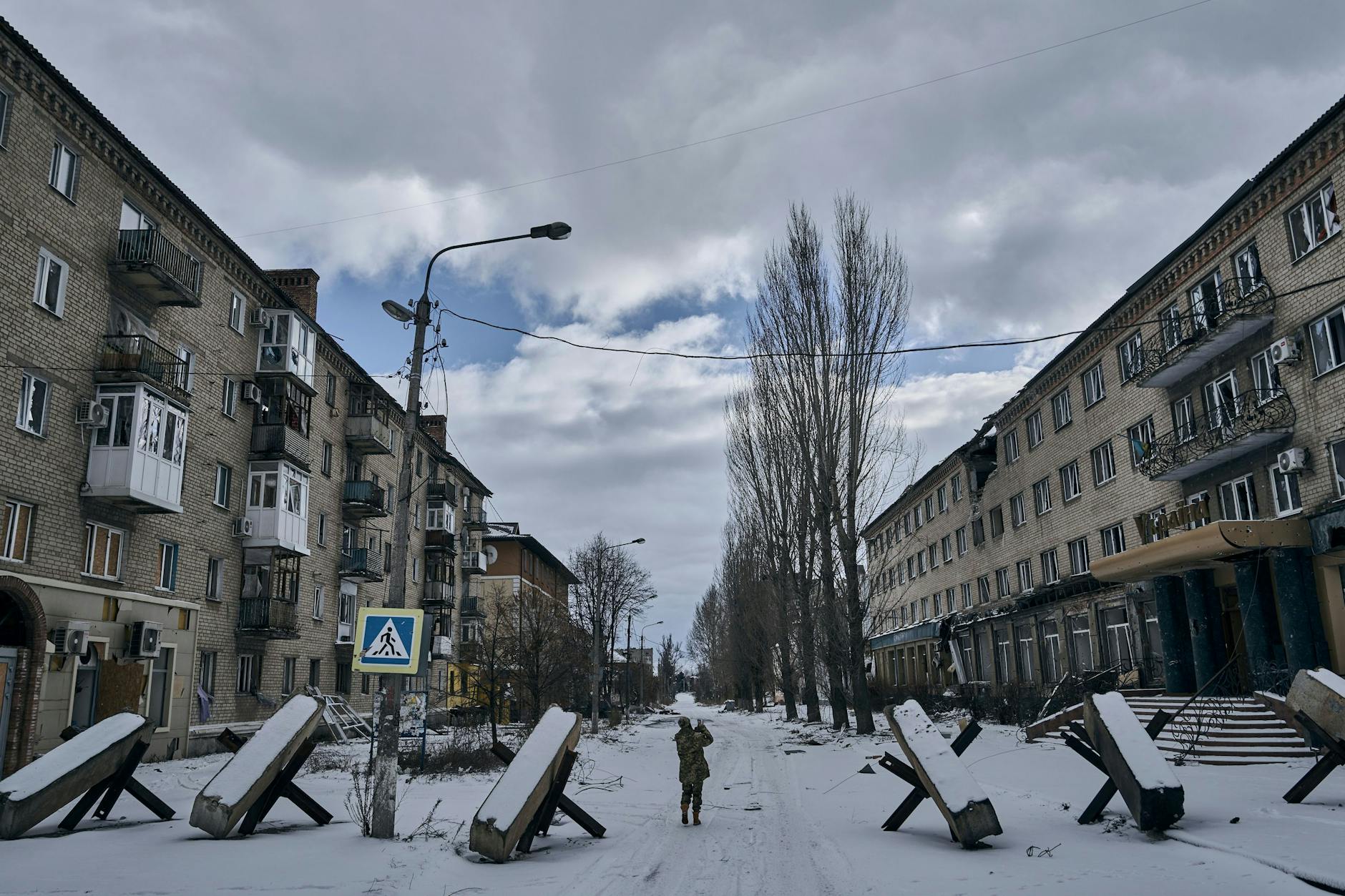 Ein Foto aus dem Februar 2023 in Bachmut. Ein ukrainischer Soldat geht eine Straße entlang, auf der Panzersperren stehen.