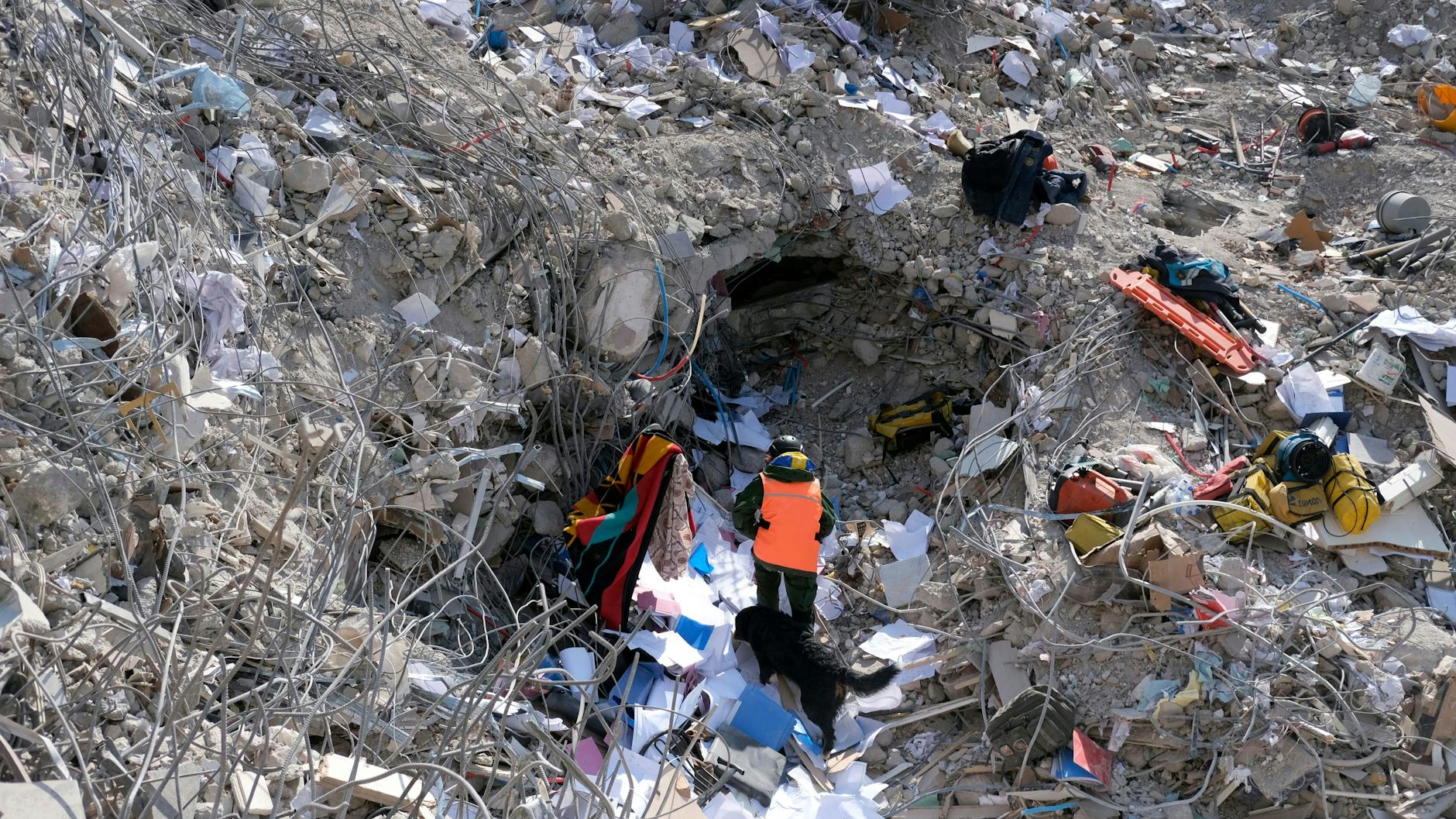 Ein Mann läuft mit seinem Hund durch die Schuttberge von Antakya.